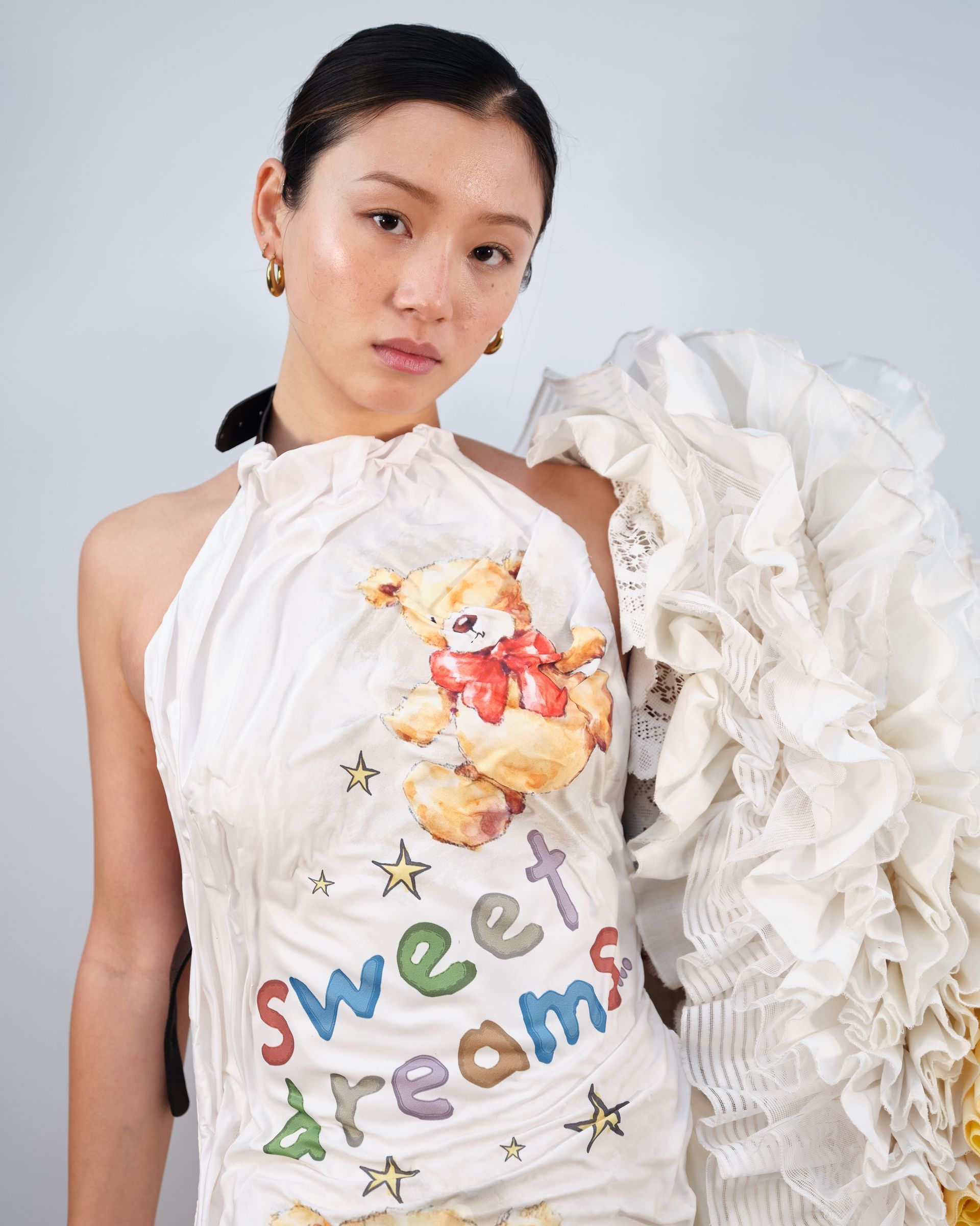 A woman is wearing a white dress with a teddy bear on it.