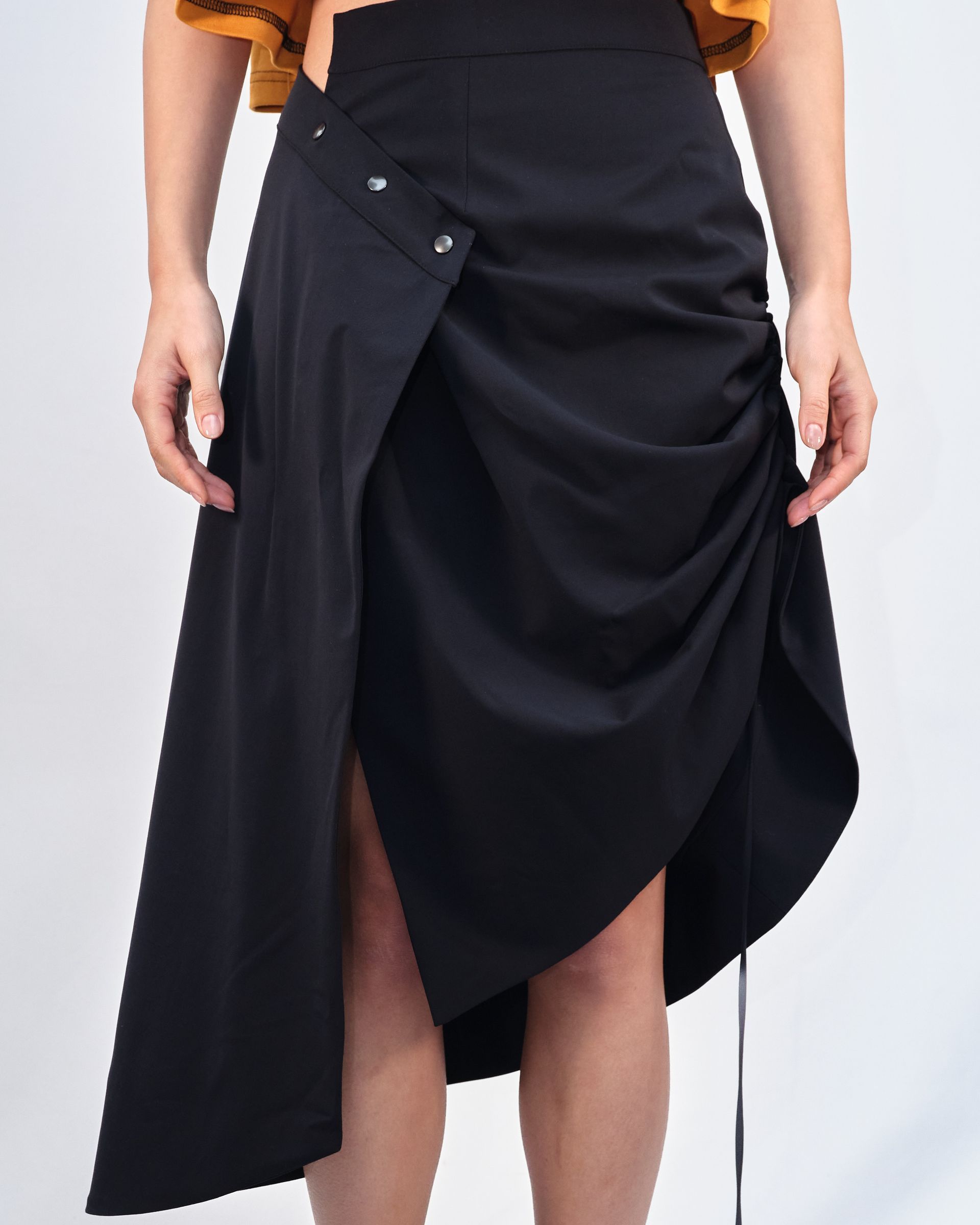 A woman is wearing a black skirt with buttons on the side