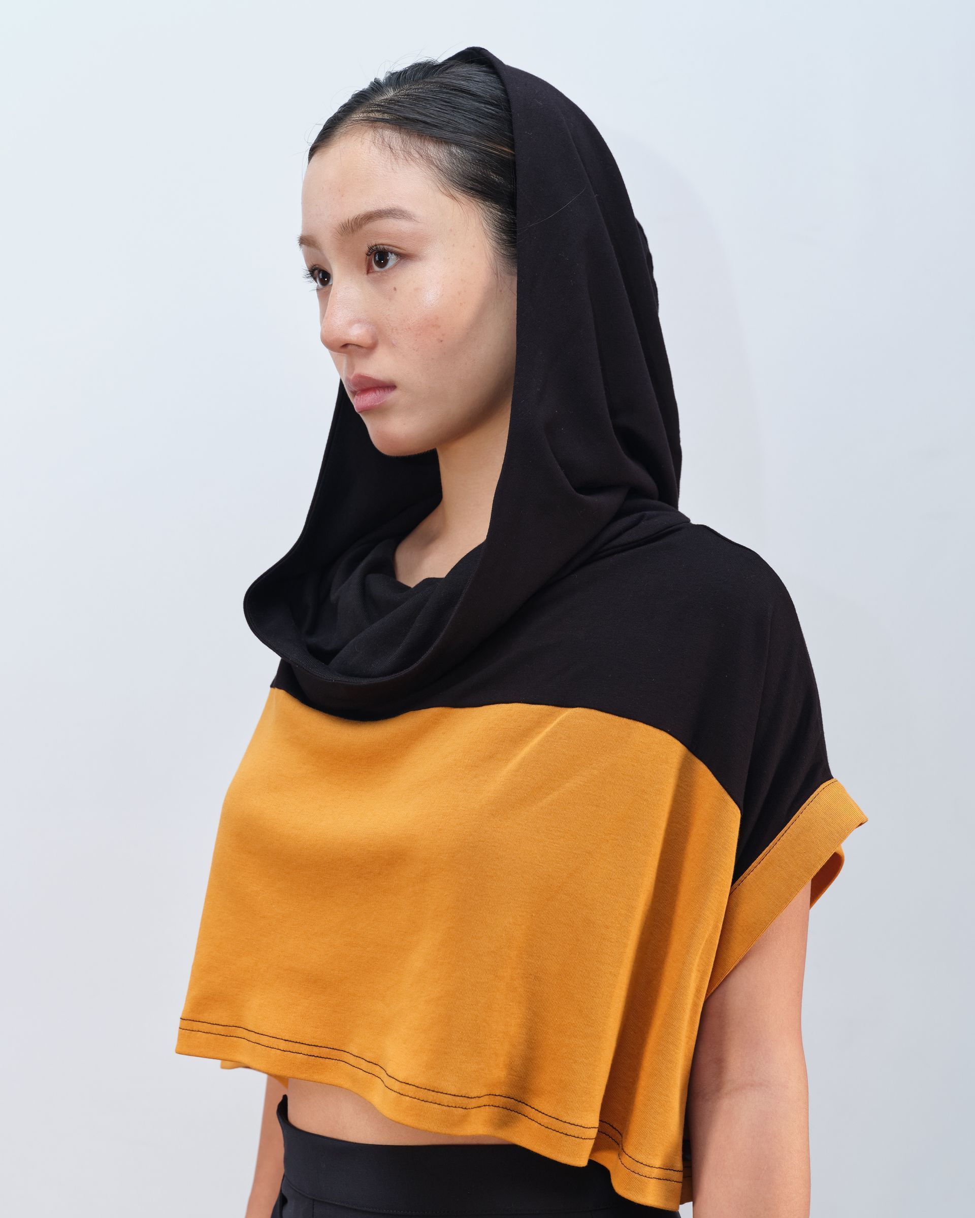 A woman wearing a black and yellow top with a hood