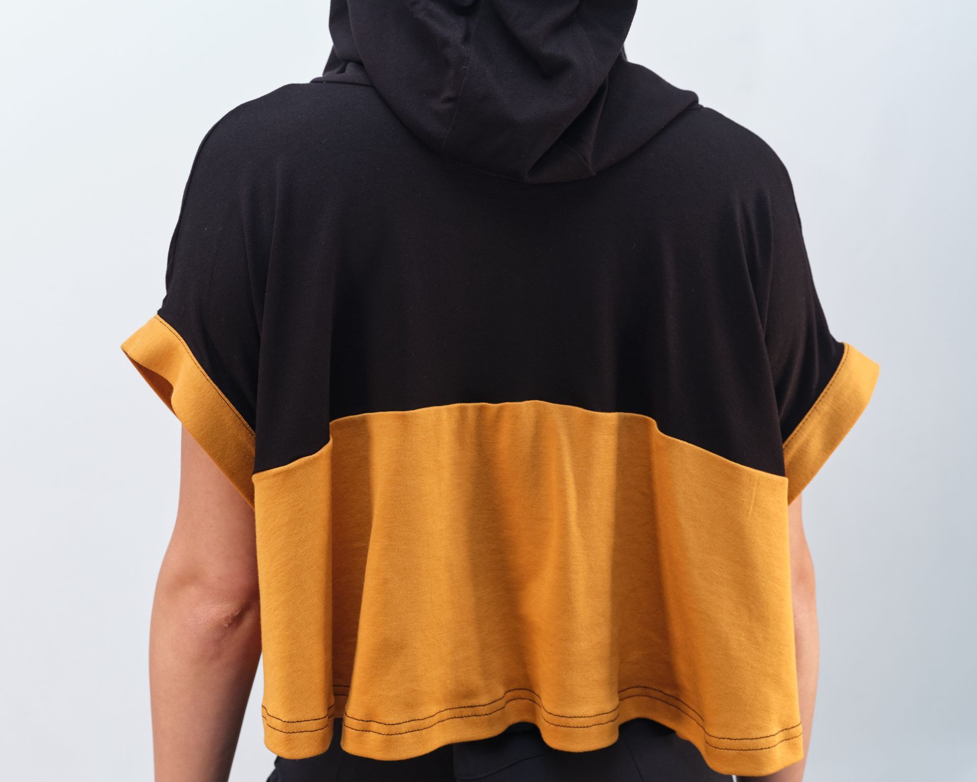 The back of a person wearing a black and yellow hoodie
