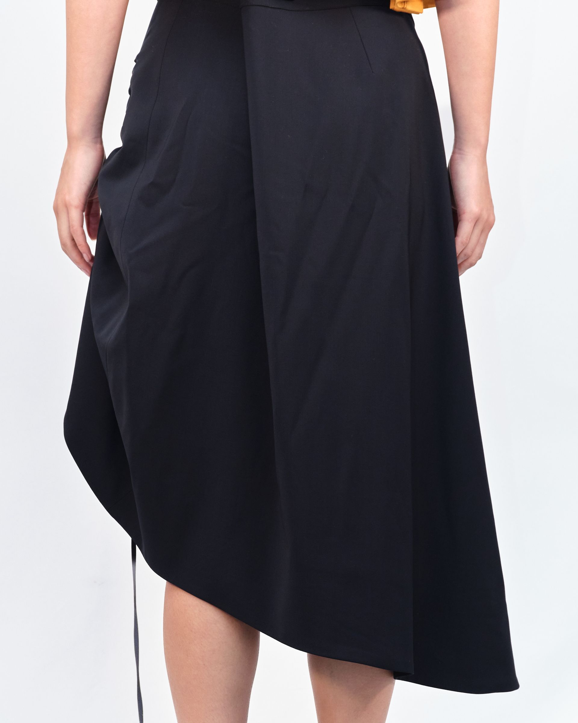 A woman is wearing a black skirt with buttons on the side