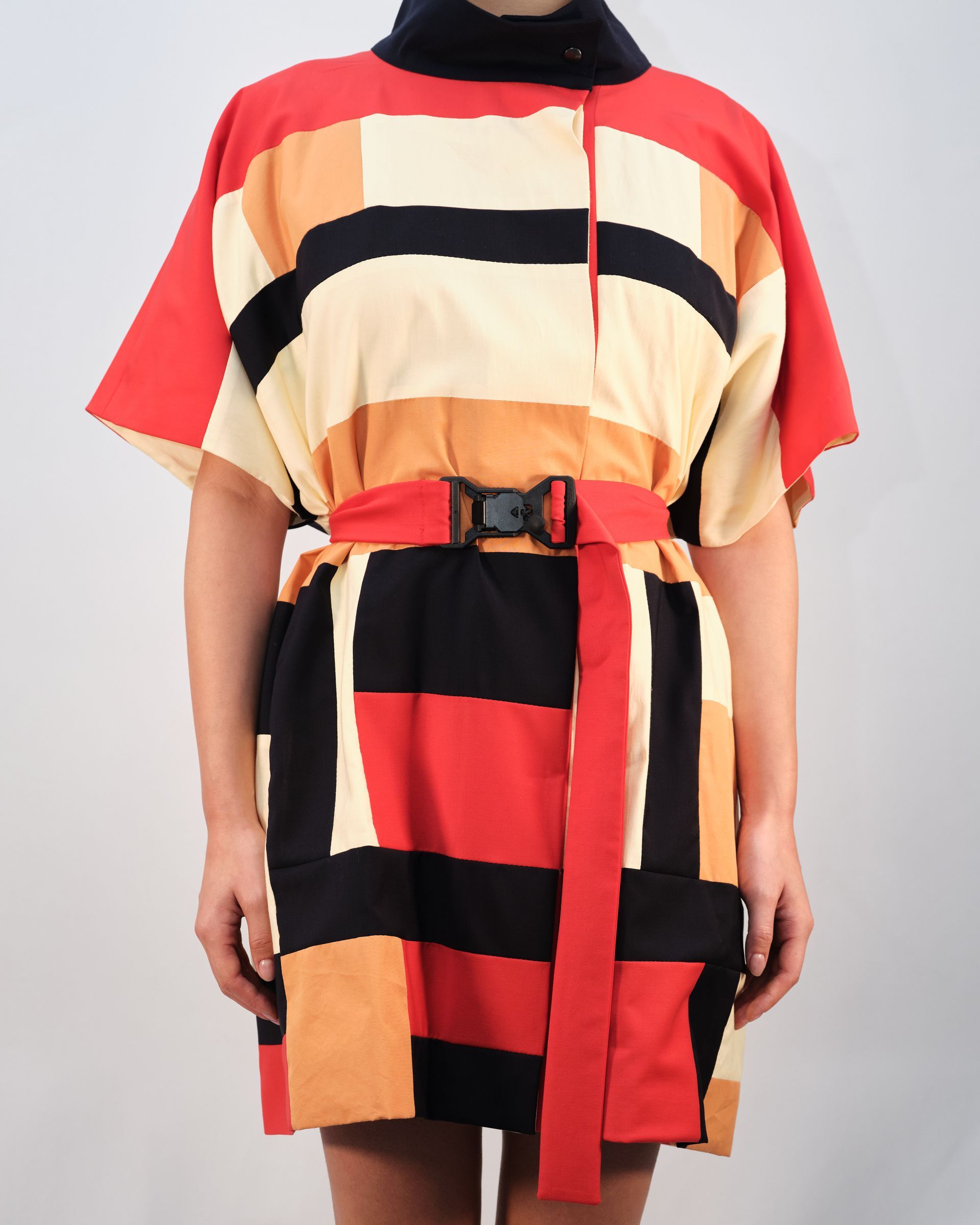 A woman wearing a colorful striped dress with a red belt