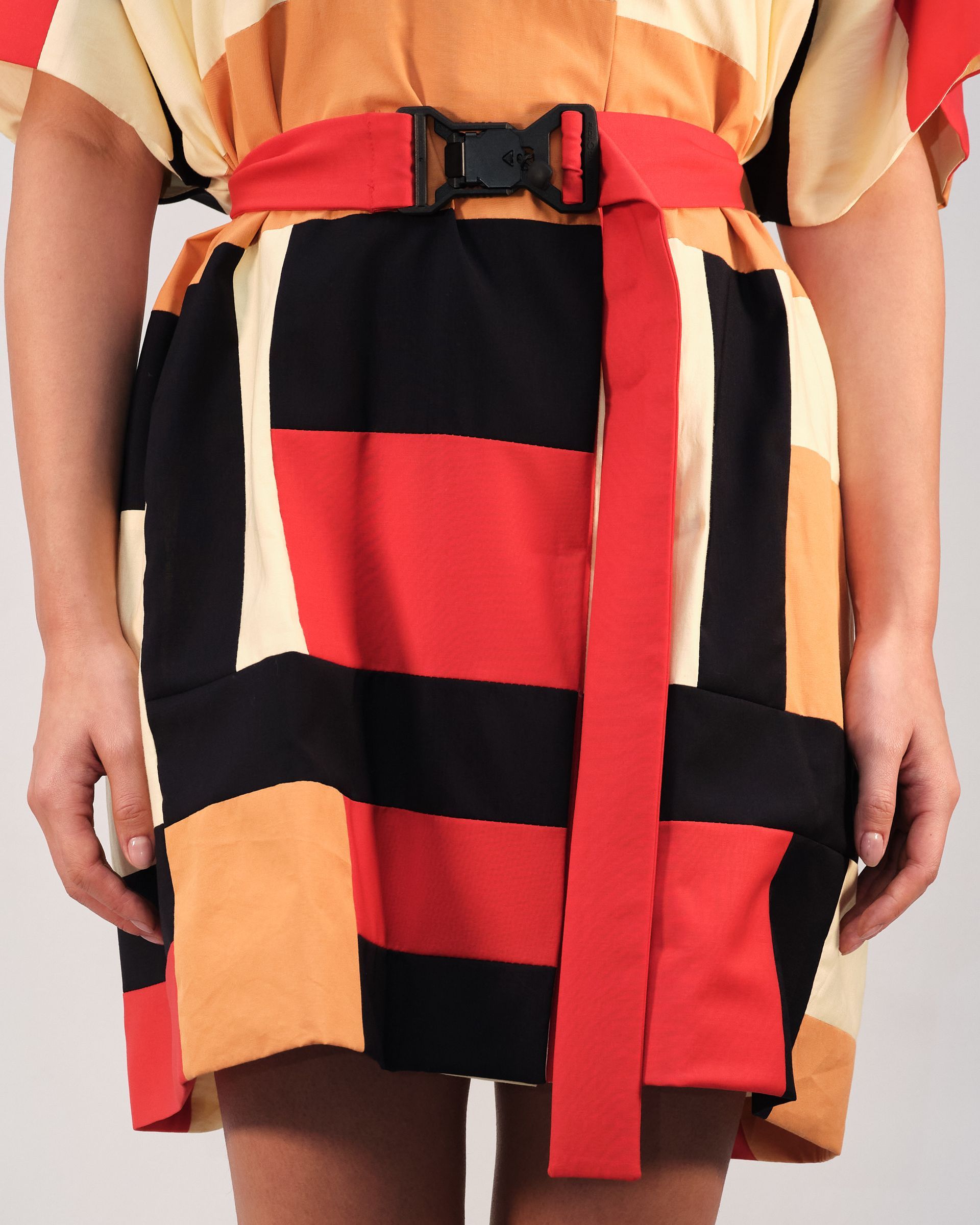 A woman wearing a striped dress with a red belt around her waist