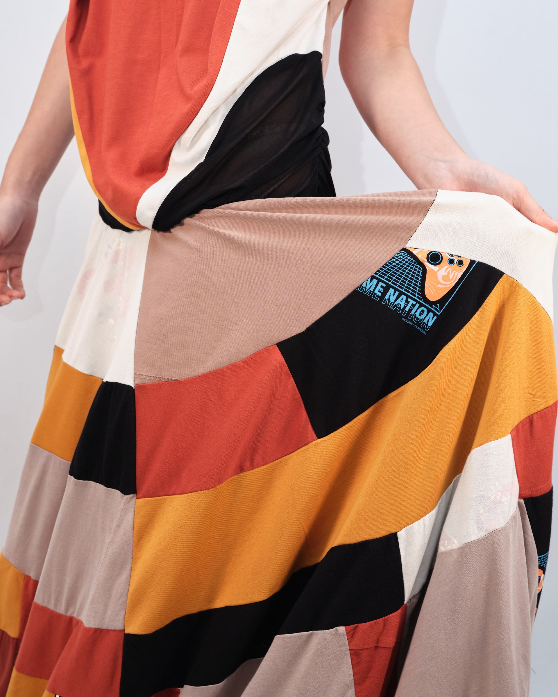 A woman in a colorful dress is standing in front of a white wall.