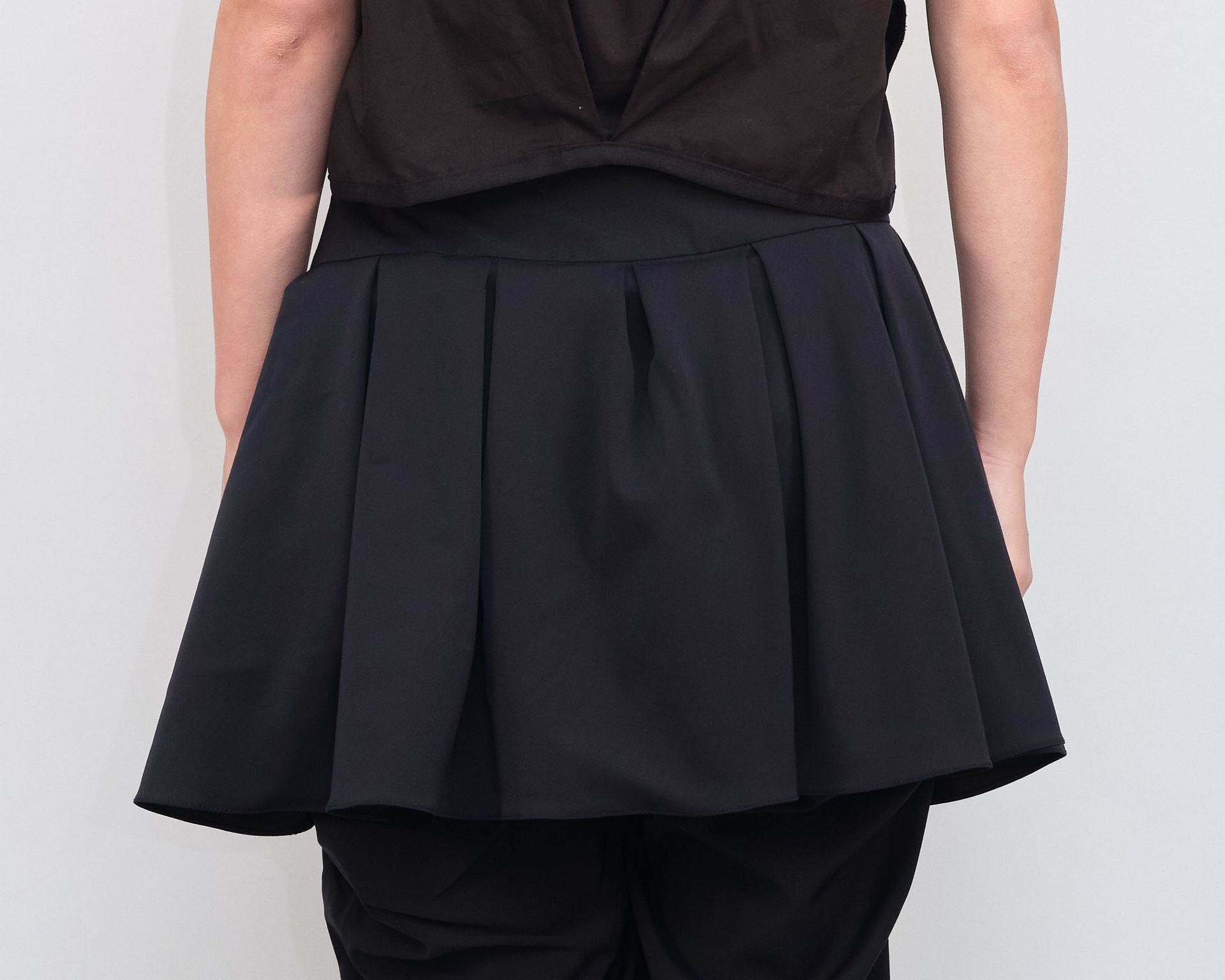 A woman wearing a black pleated skirt and a black shirt