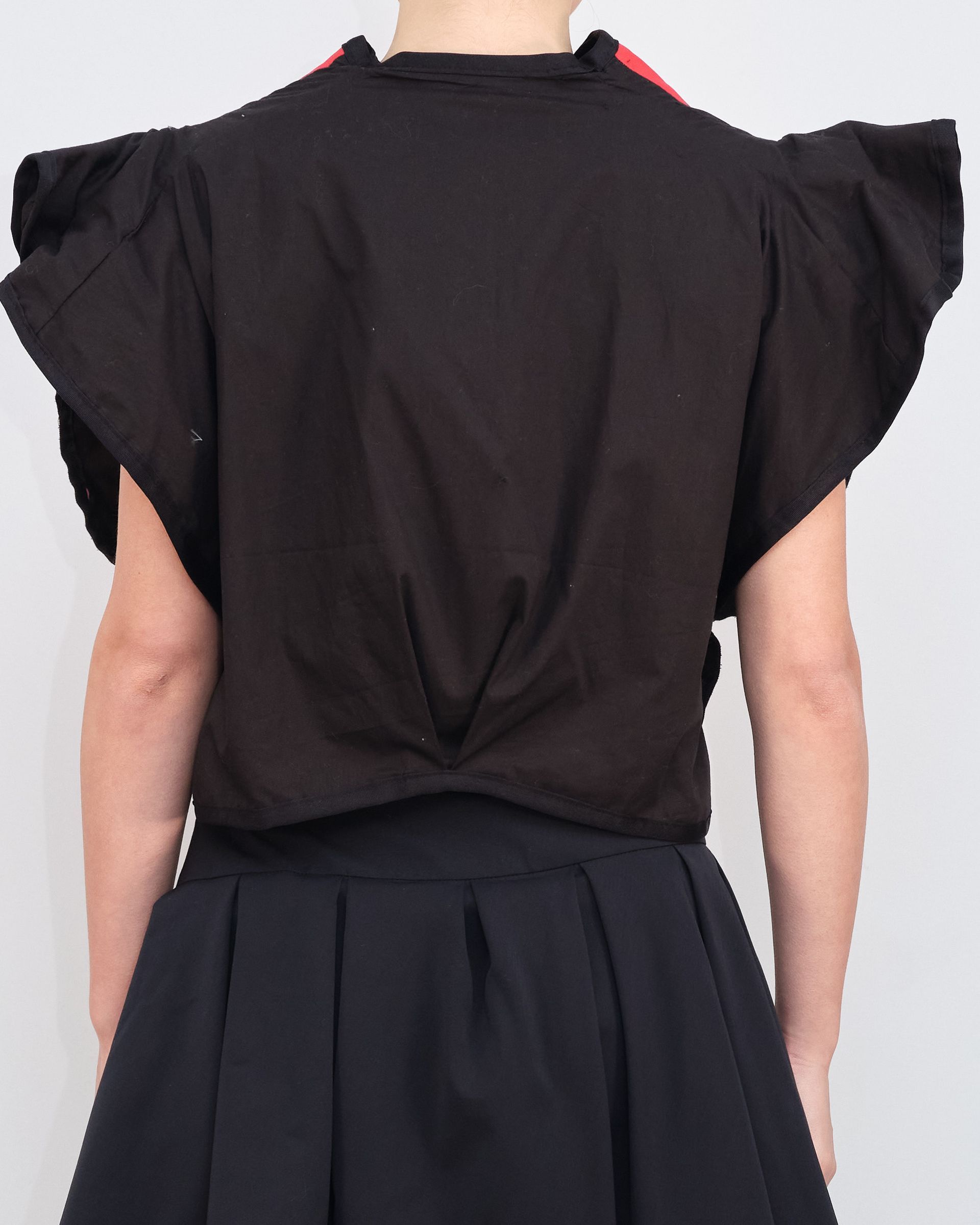 The back of a woman wearing a black shirt and black skirt