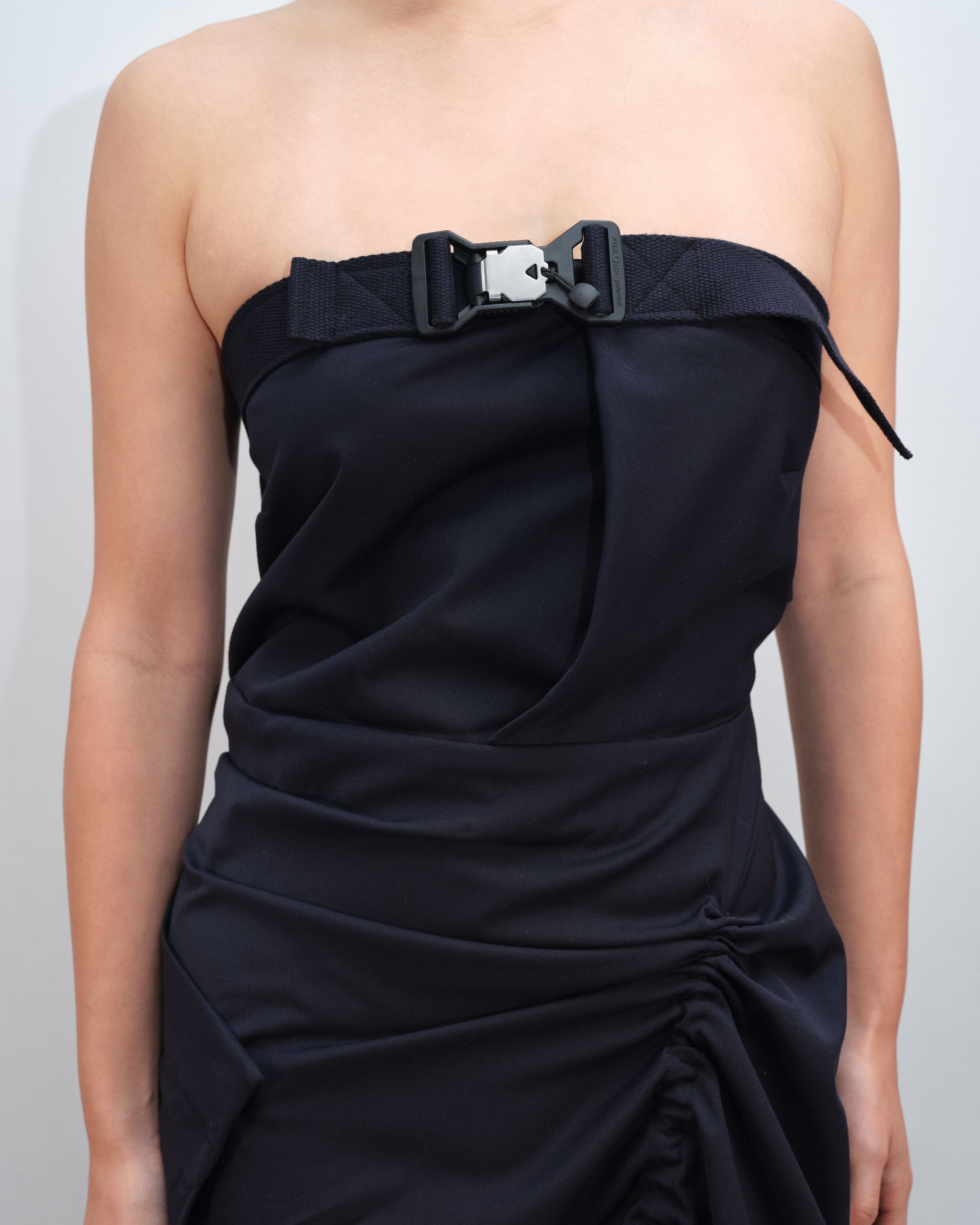 A woman is wearing a strapless black dress with a black belt