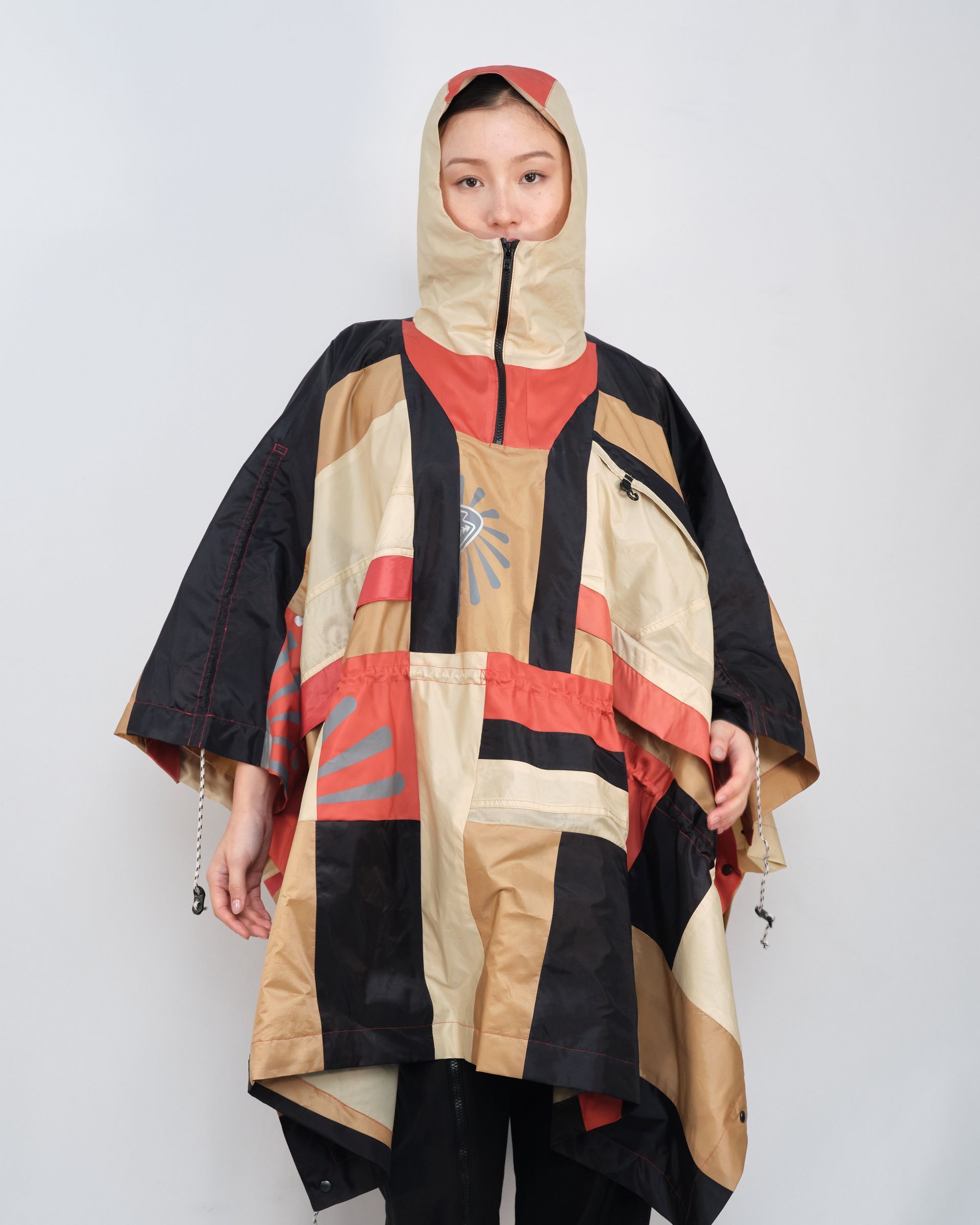 A woman is wearing a colorful poncho with a hood.
