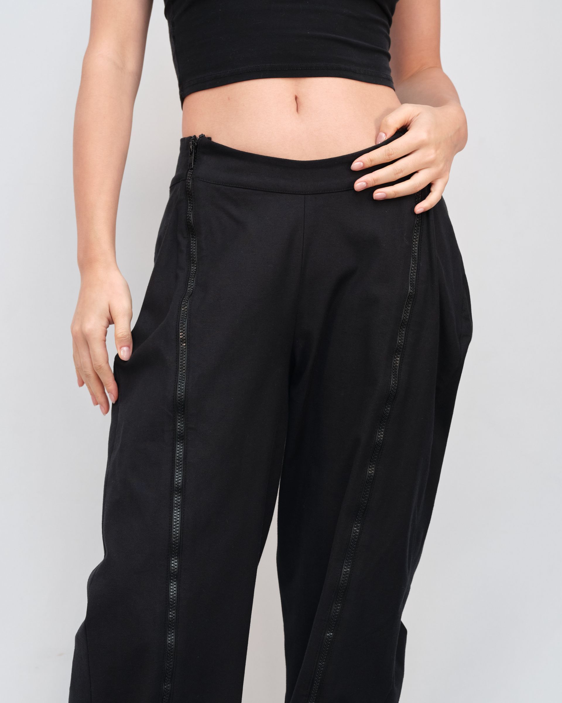 A woman is wearing a crop top and black pants