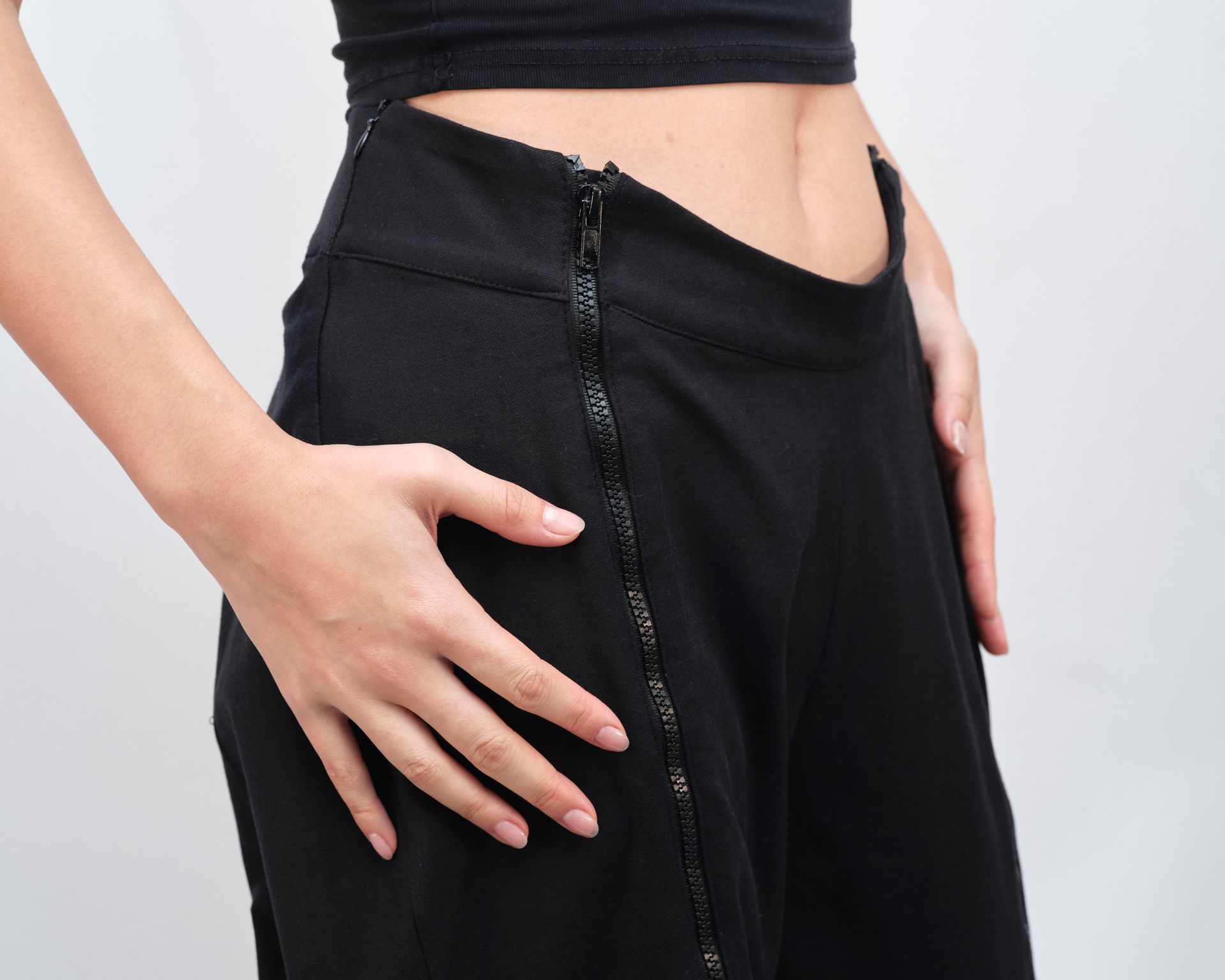 A woman wearing black pants with a zipper on the side