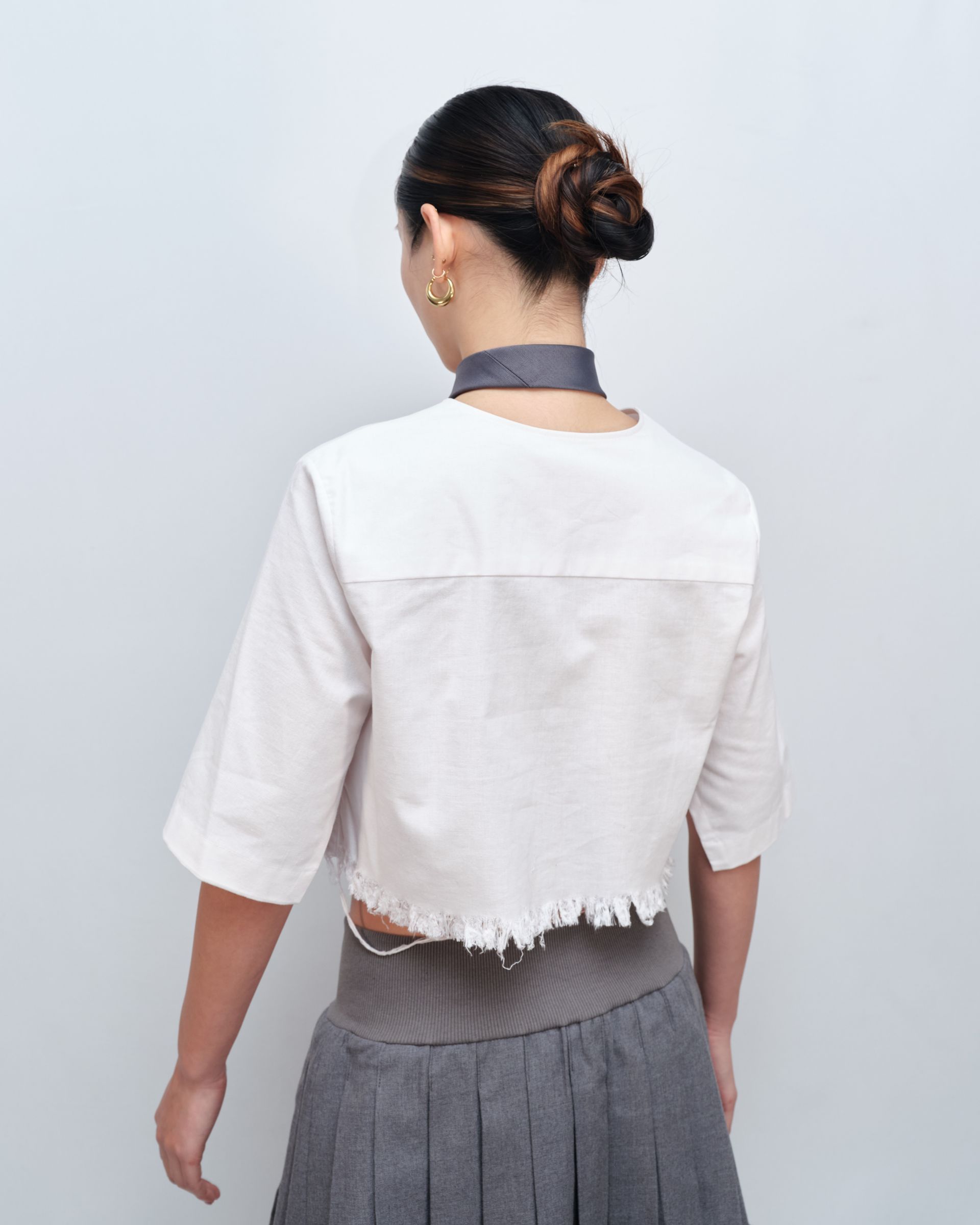 The back of a woman wearing a white shirt and a grey skirt
