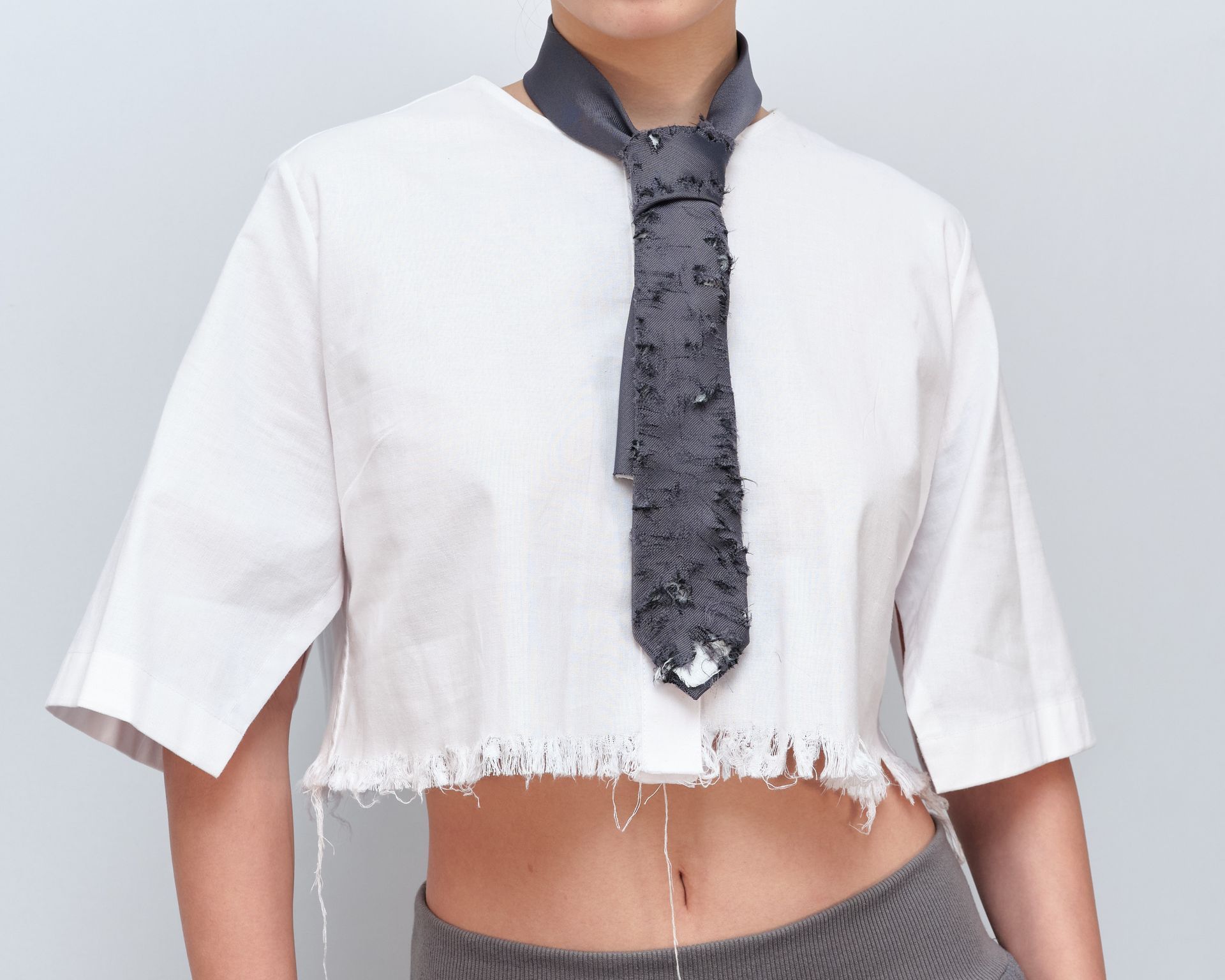 A person wearing a crop top with a tie around their neck