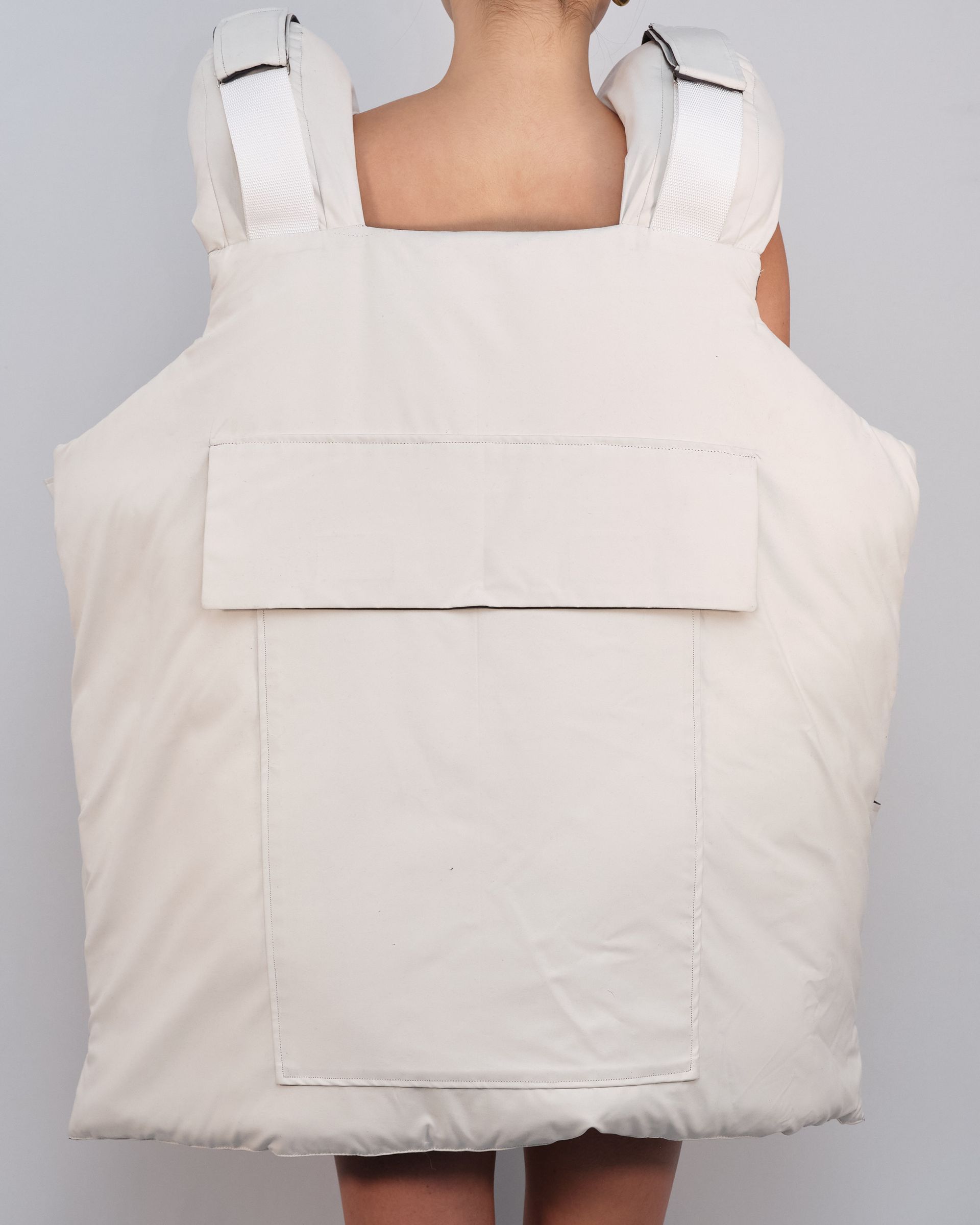 A woman is wearing a white vest with a pocket on the back