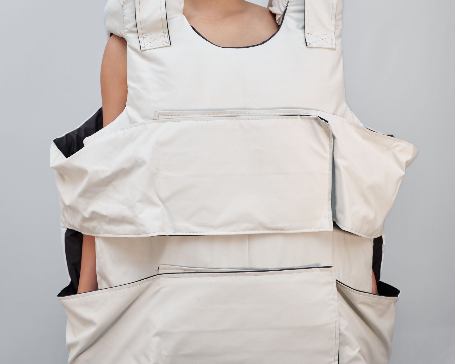 A woman wearing a white vest is holding a white bag.