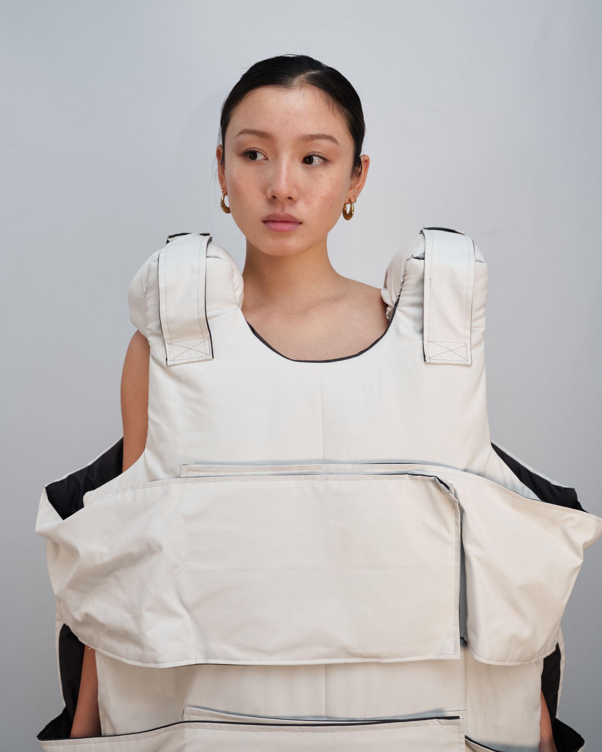 A woman wearing a white vest is holding a white bag.