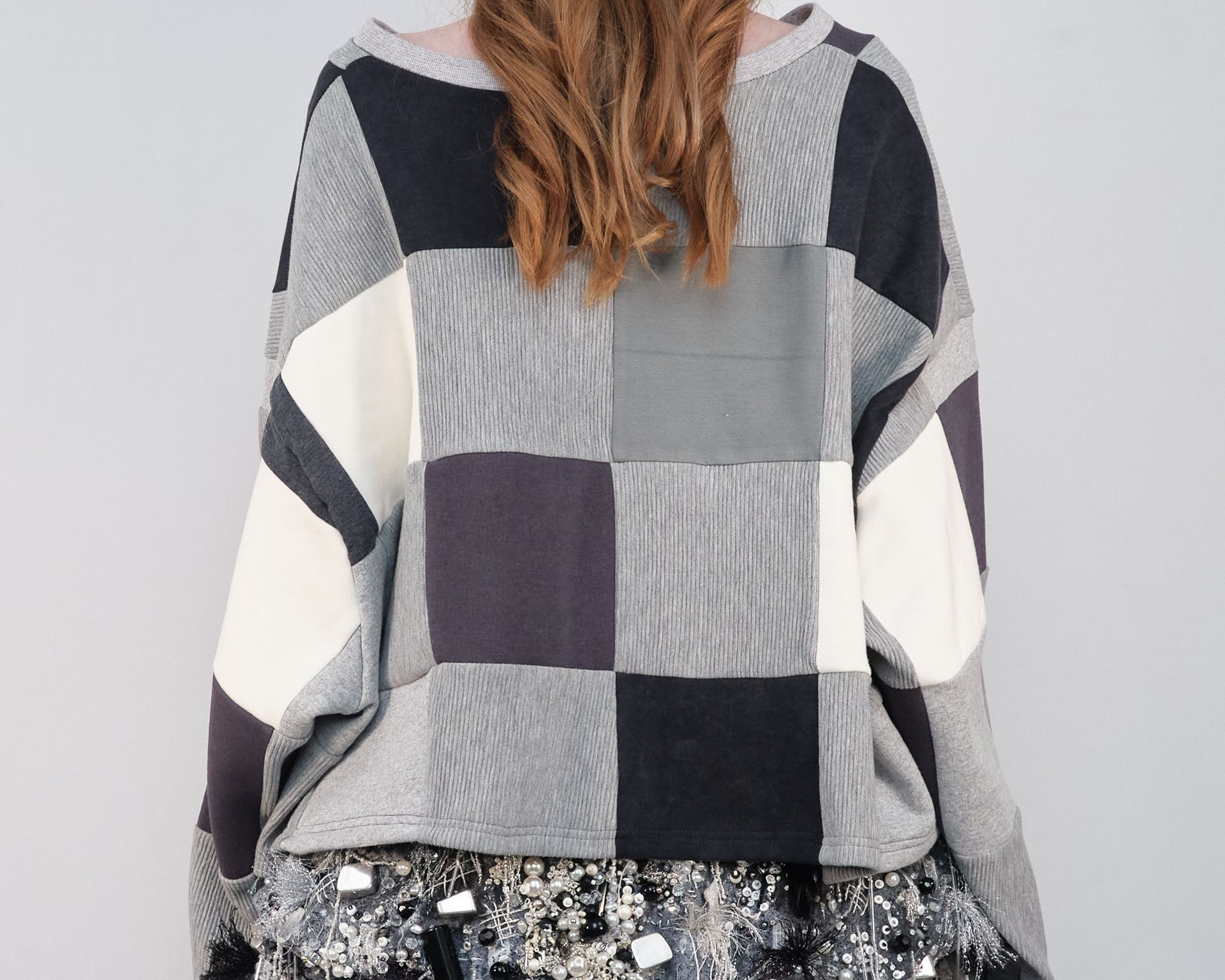 A woman wearing a plaid sweater and sequined skirt