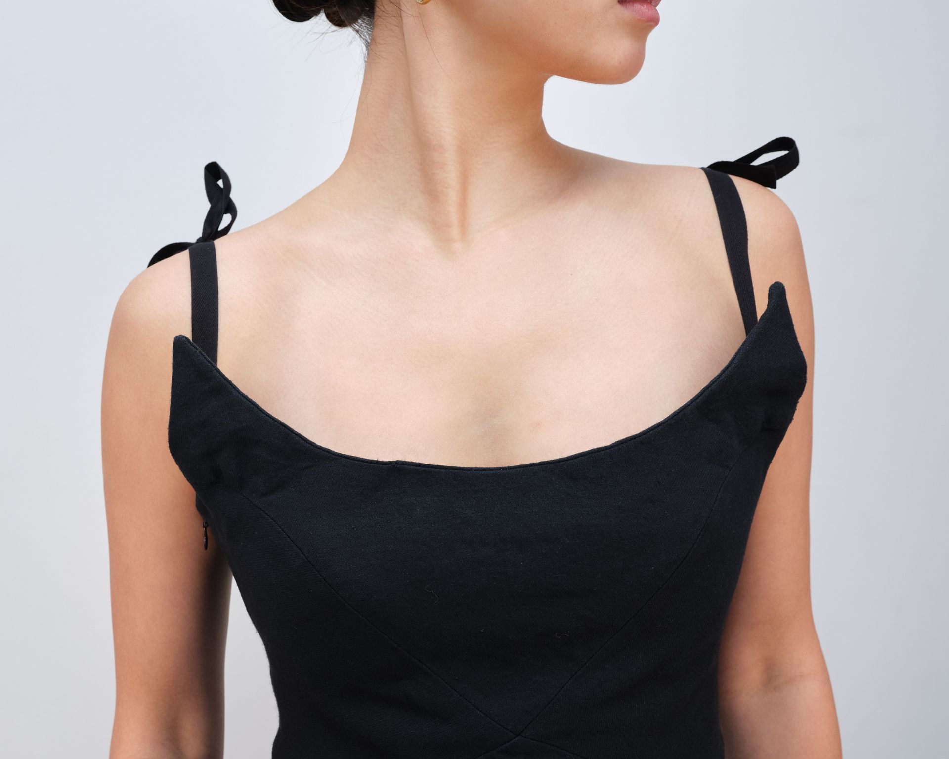 A woman is wearing a black tank top with straps on the shoulder