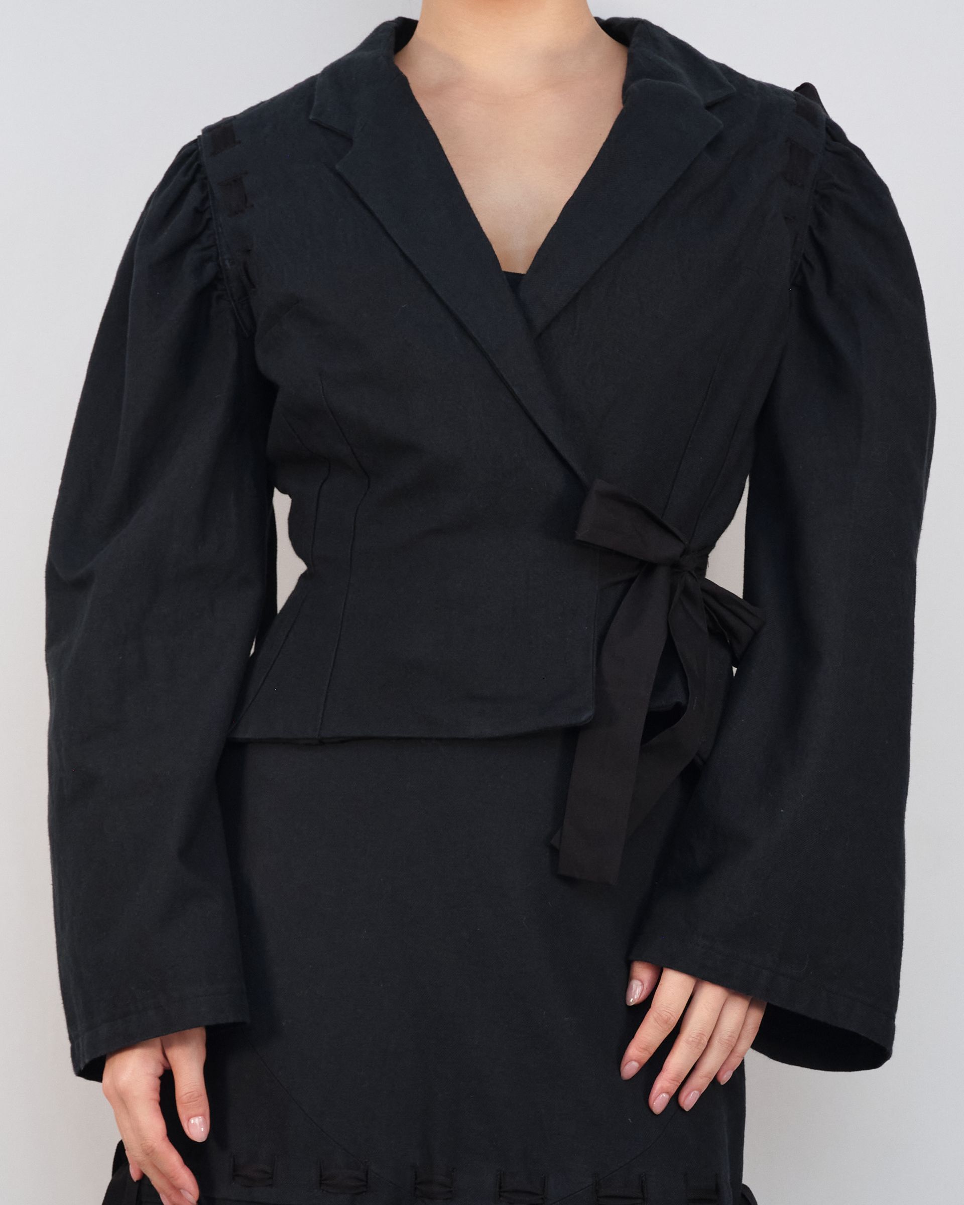 A woman is wearing a black wrap top with puffed sleeves