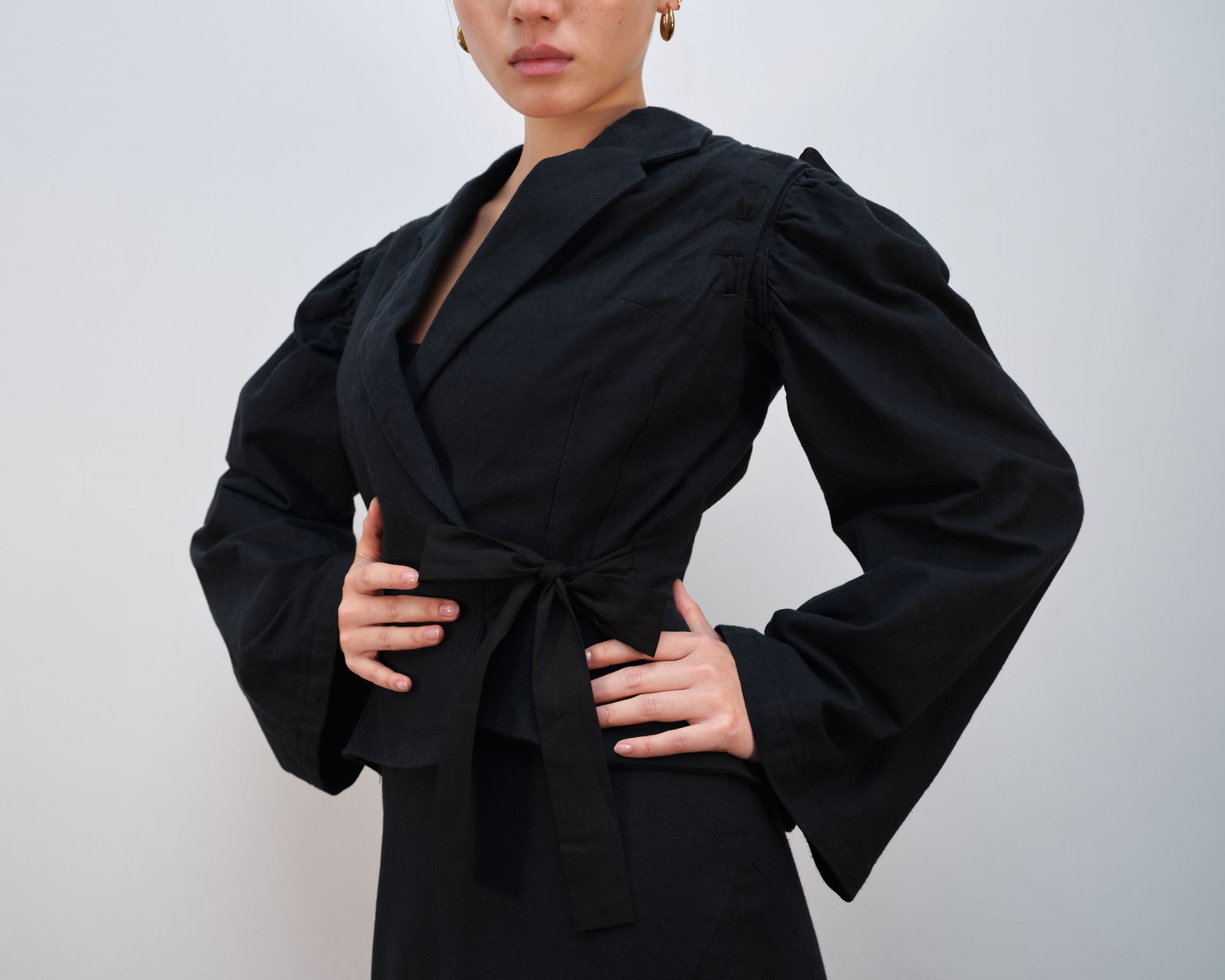 A woman is wearing a black dress and a black vest