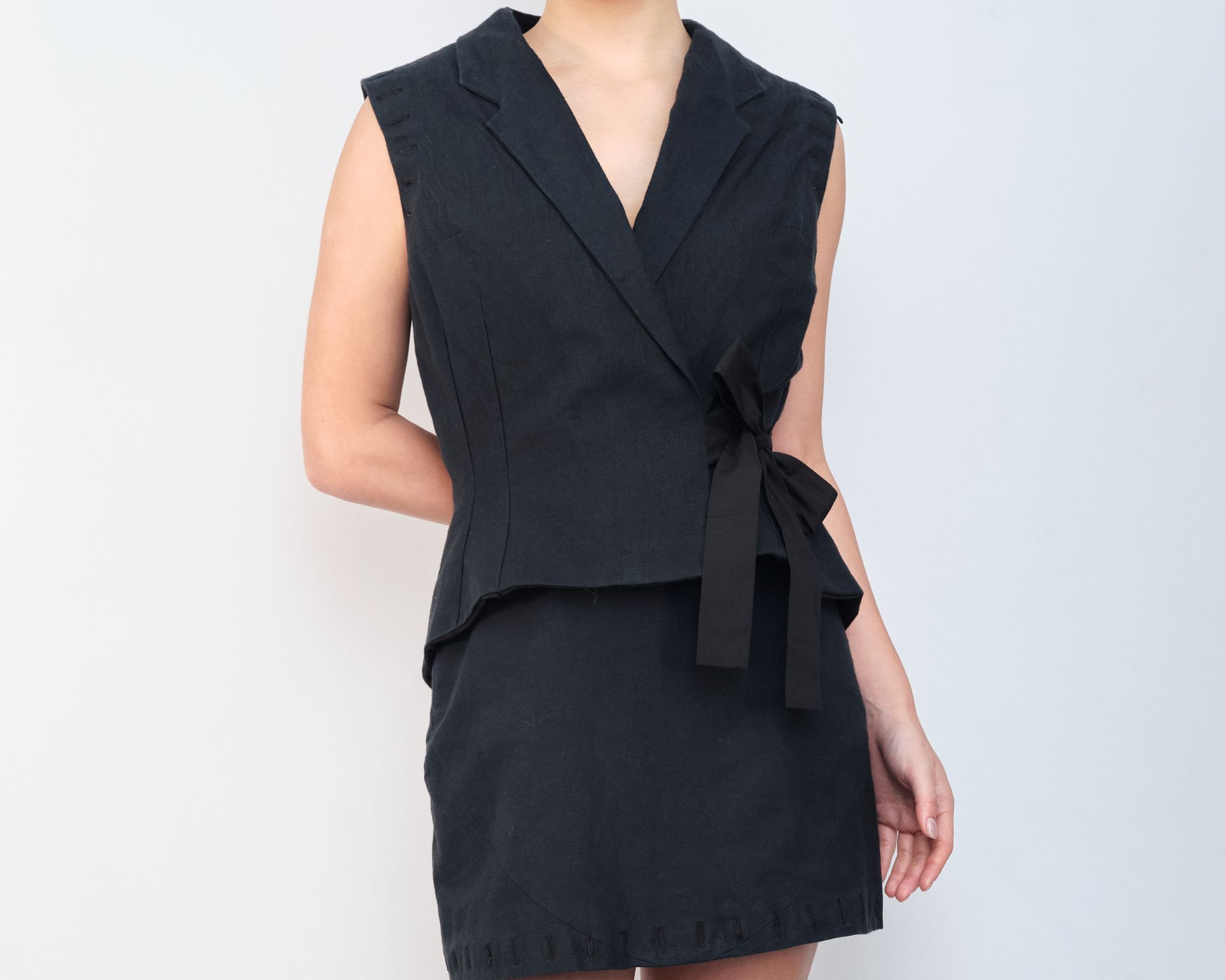 A woman in a black dress is standing in front of a white wall