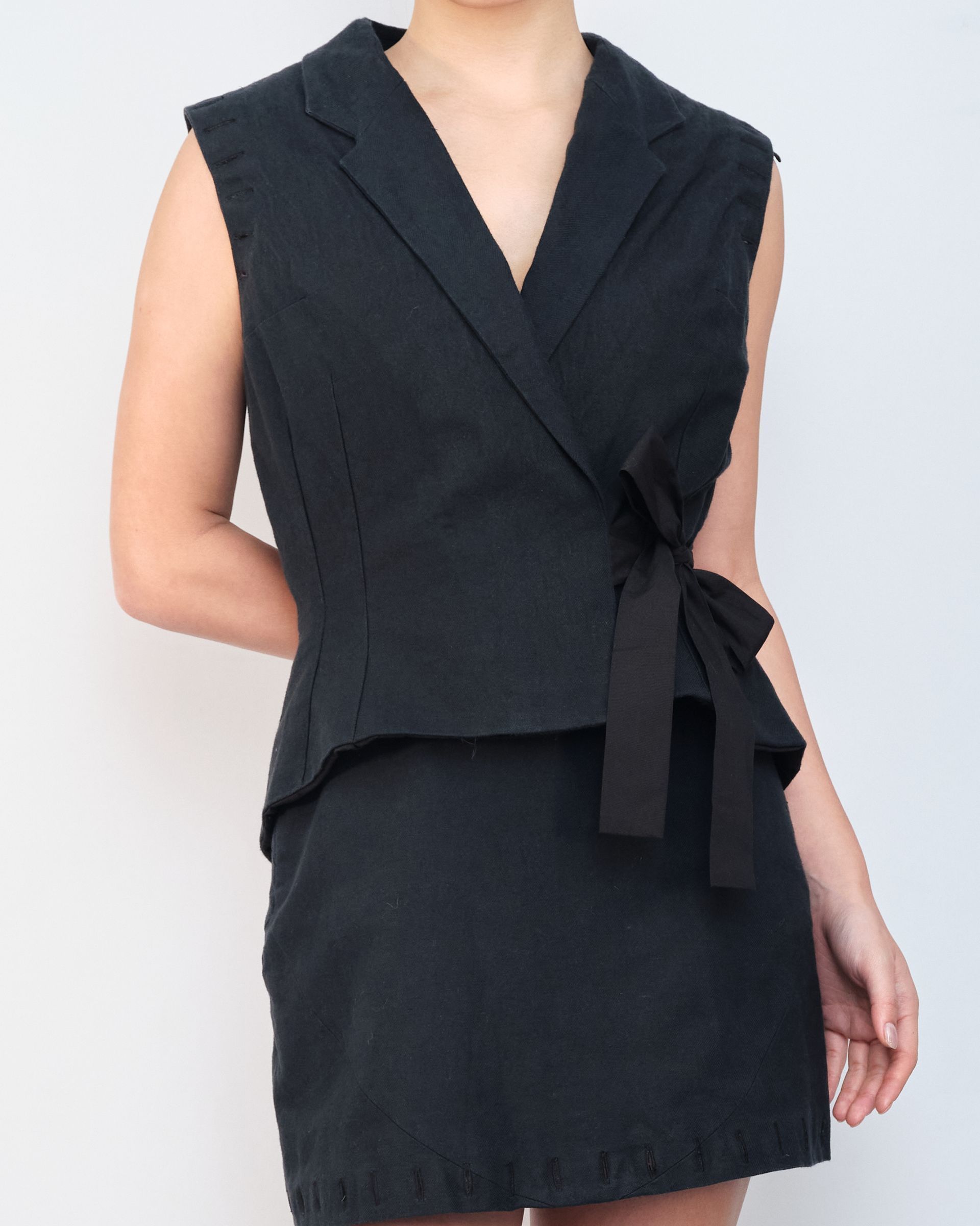 A woman is wearing a black dress and a black vest
