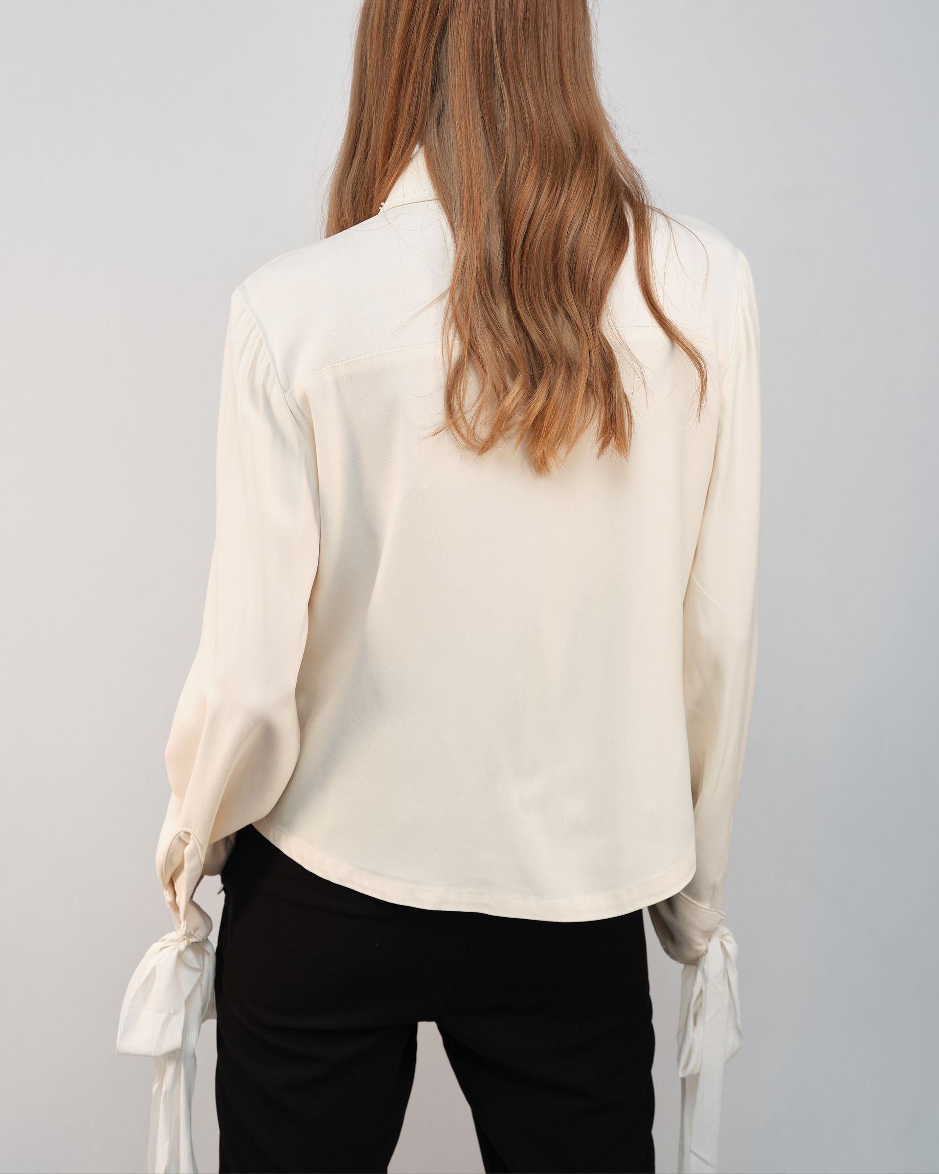 The back of a woman wearing a white shirt and black pants.