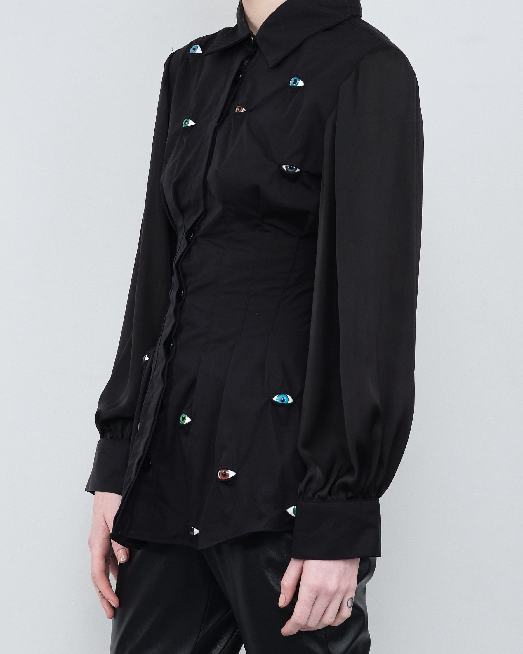 A woman wearing a black jacket with patches that say stop looking at me