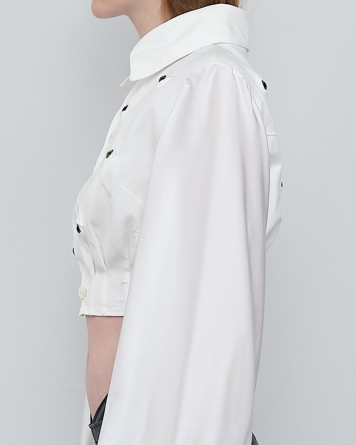 A woman is wearing a white shirt with black polka dots on the sleeves.