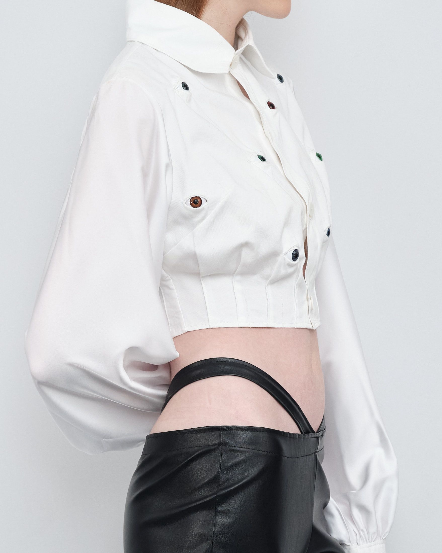 A woman is wearing a white crop top and black pants.