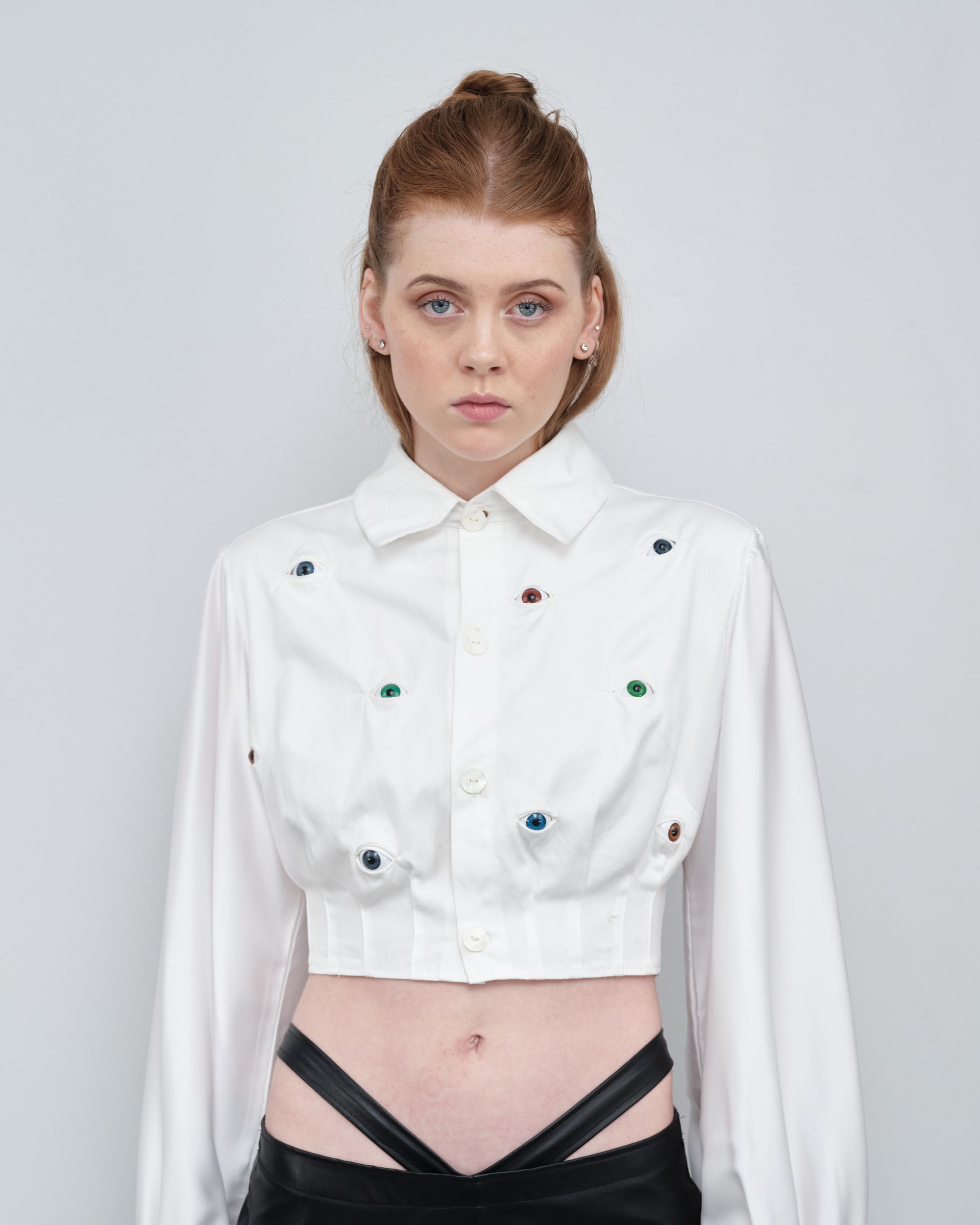 A woman is wearing a white crop top and black pants.