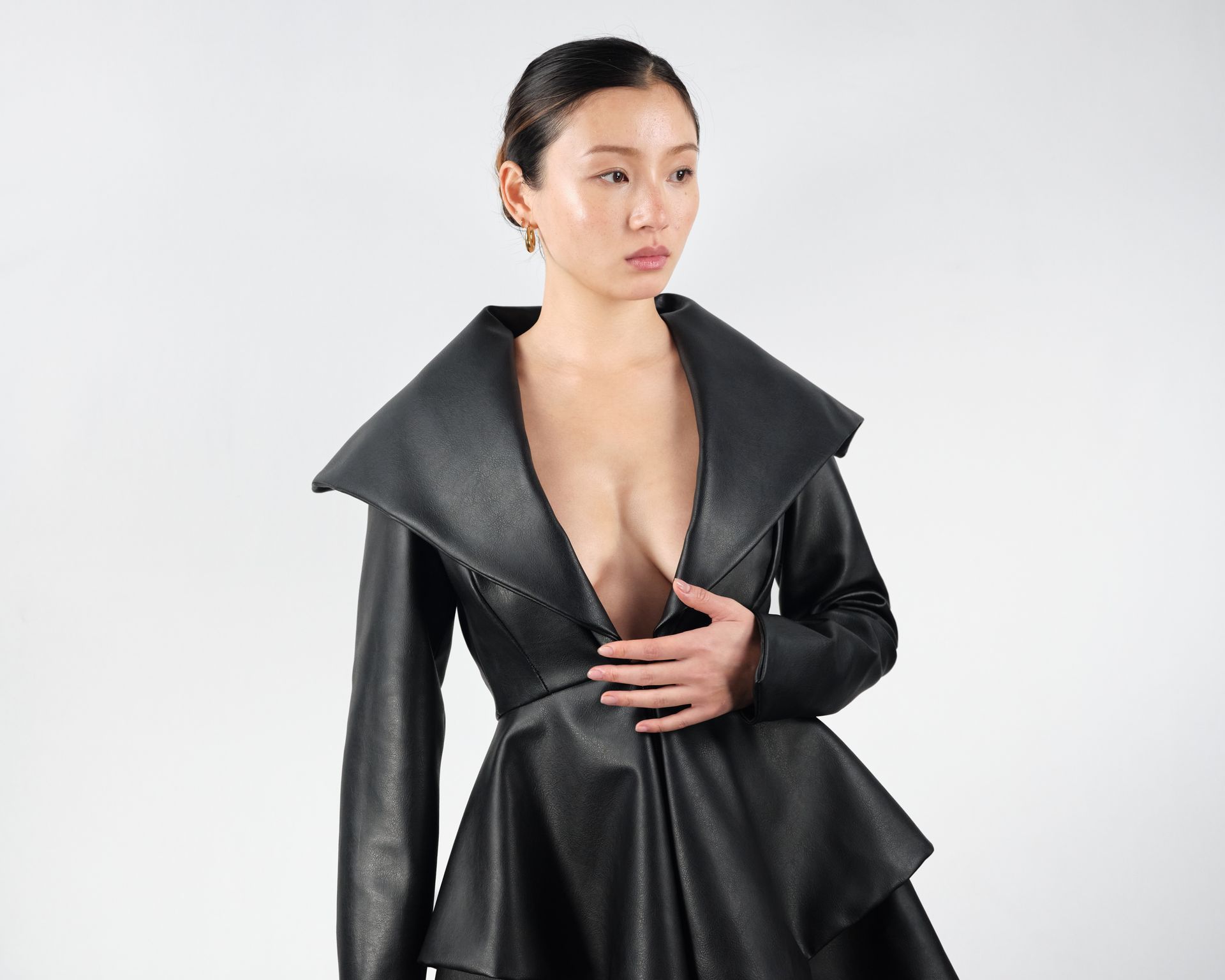 A woman is wearing a black leather jacket with a plunging neckline.