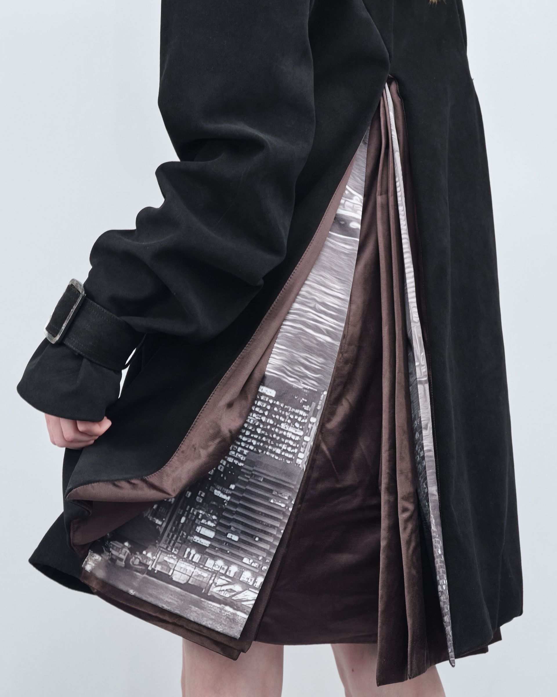 A woman is wearing a black coat and a brown skirt