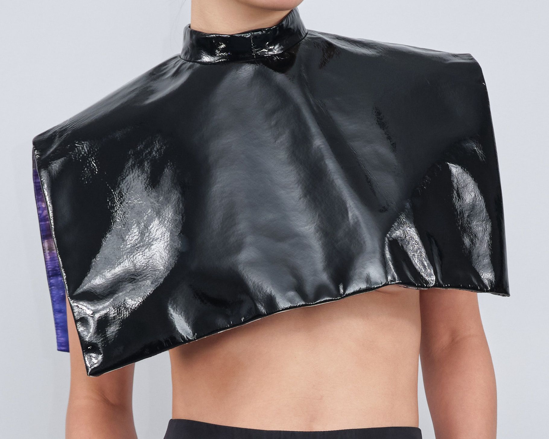 A person without a shirt is wearing a black cape