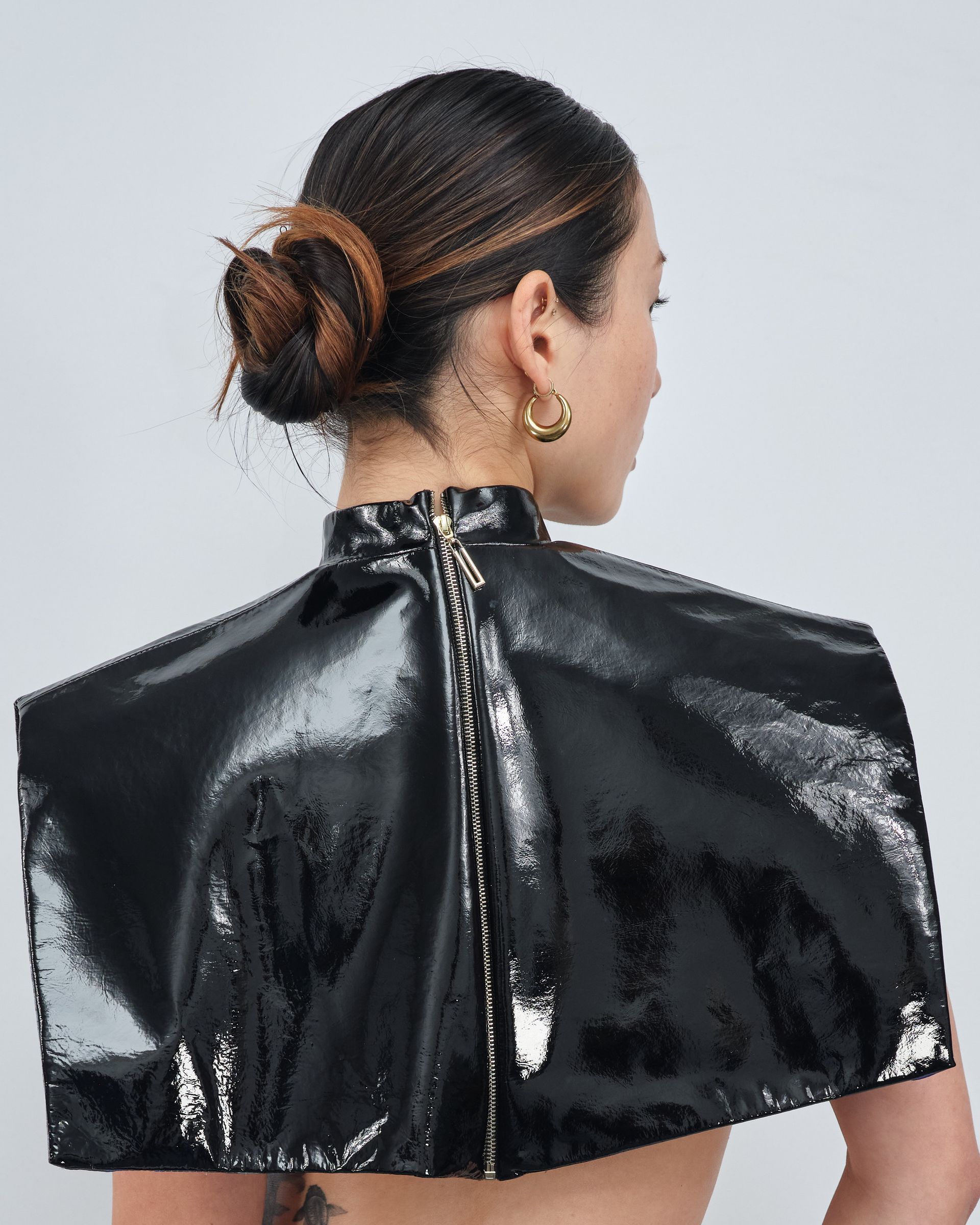A woman wearing a black cape with a zipper on the back