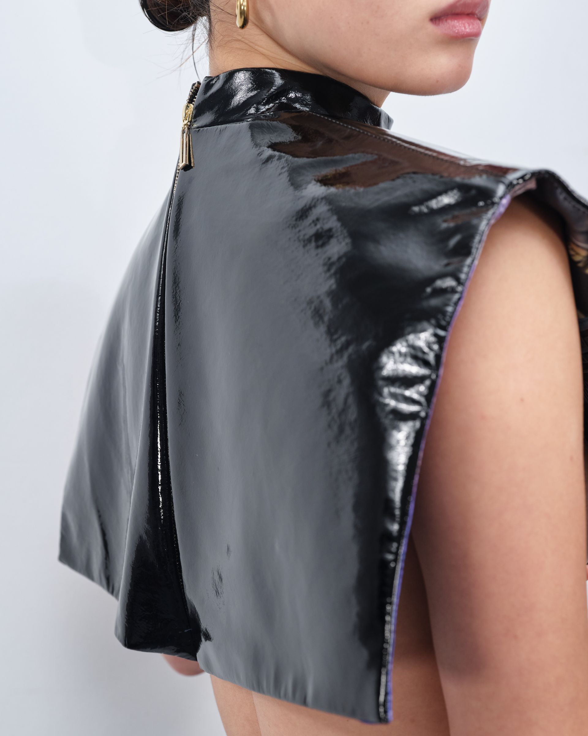 A woman wearing a black cape with a zipper on the back