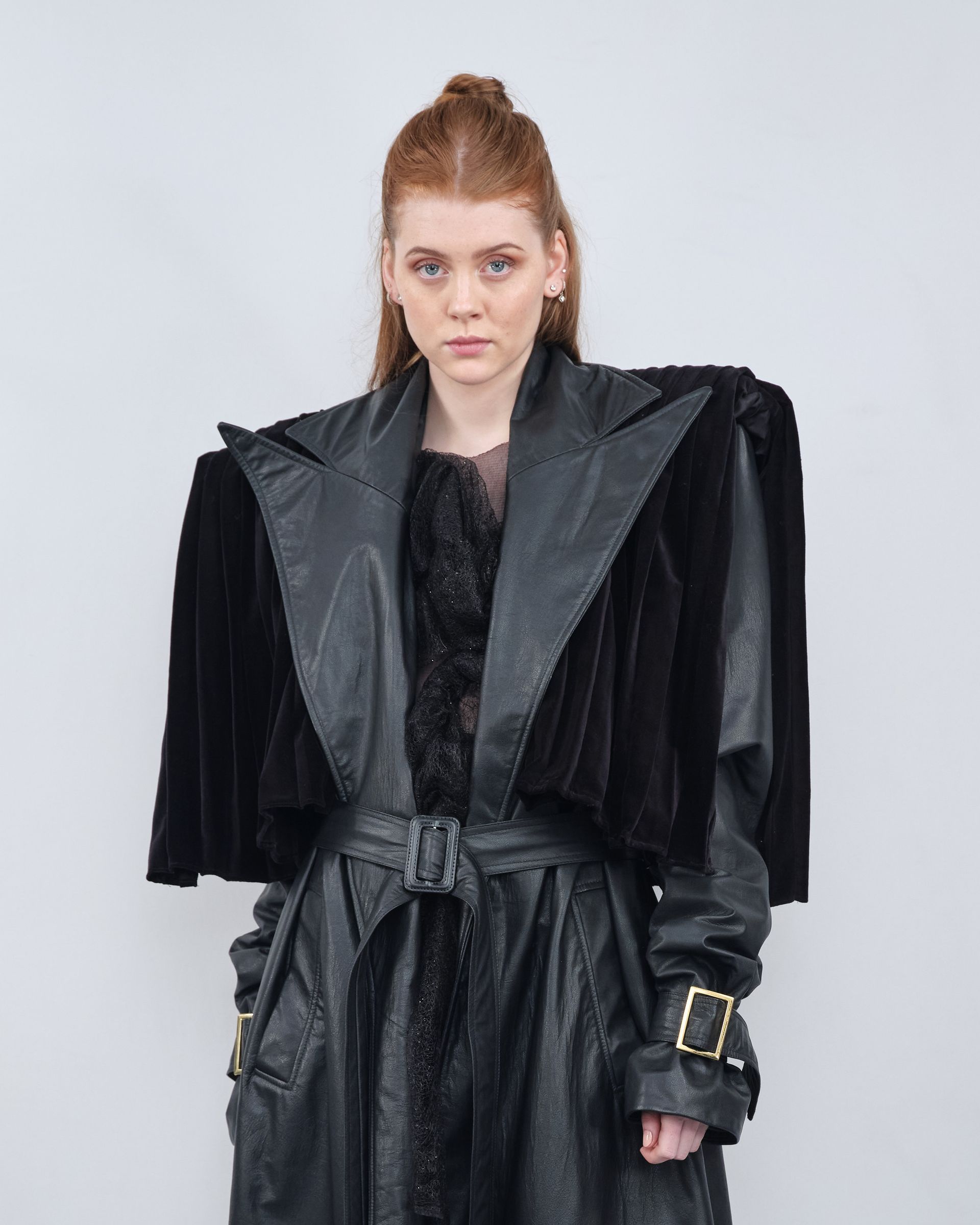 A woman is wearing a black leather coat and a black fur cape.