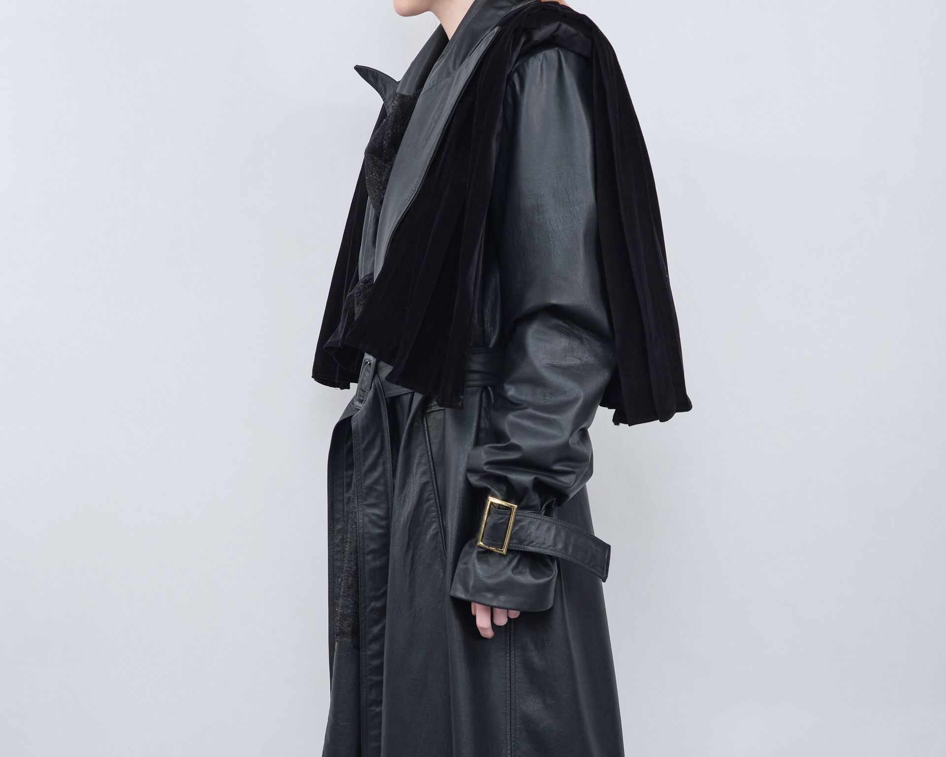 A woman is wearing a black leather trench coat and a black sweater.