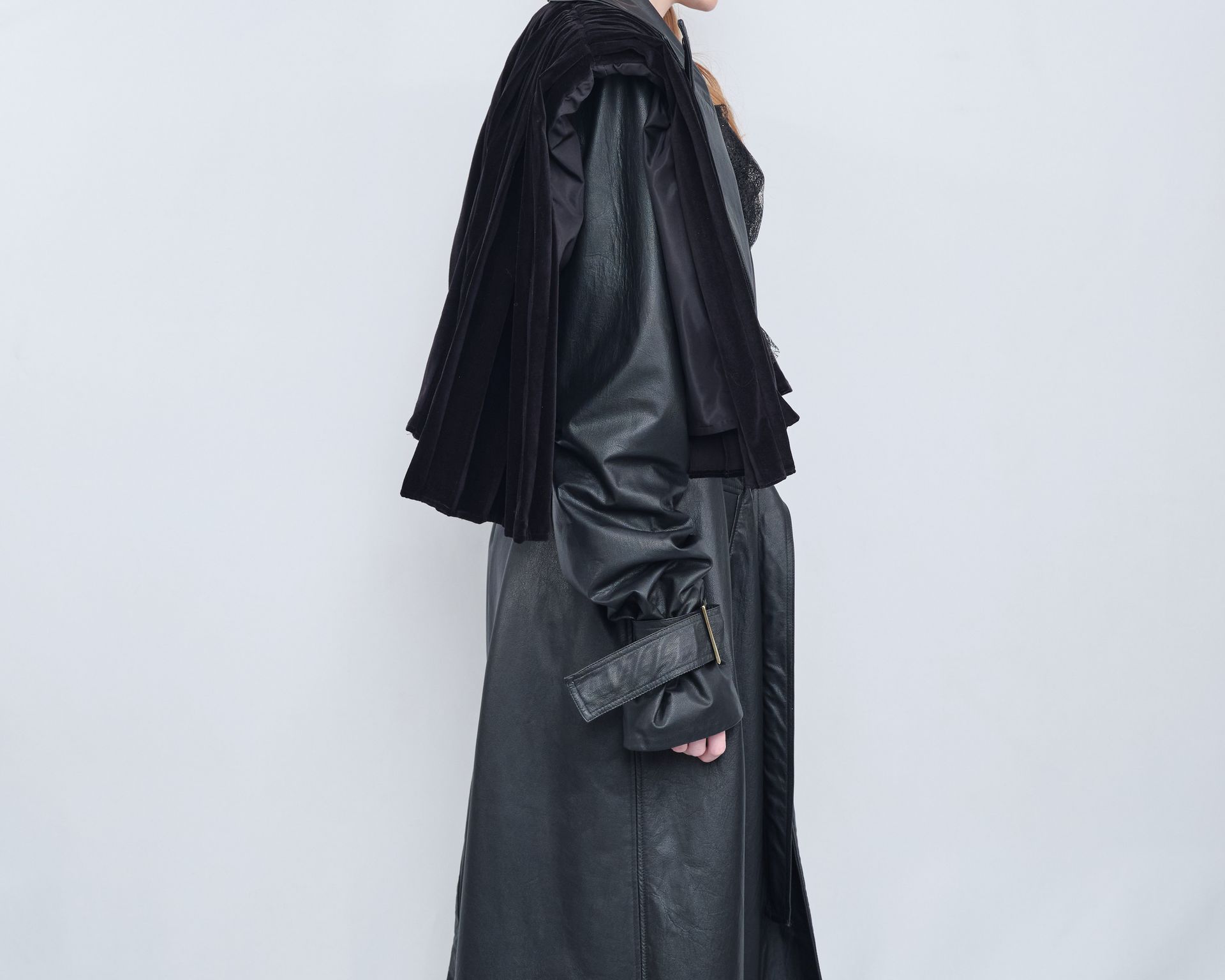 A woman is wearing a black leather coat and a black fur cape.