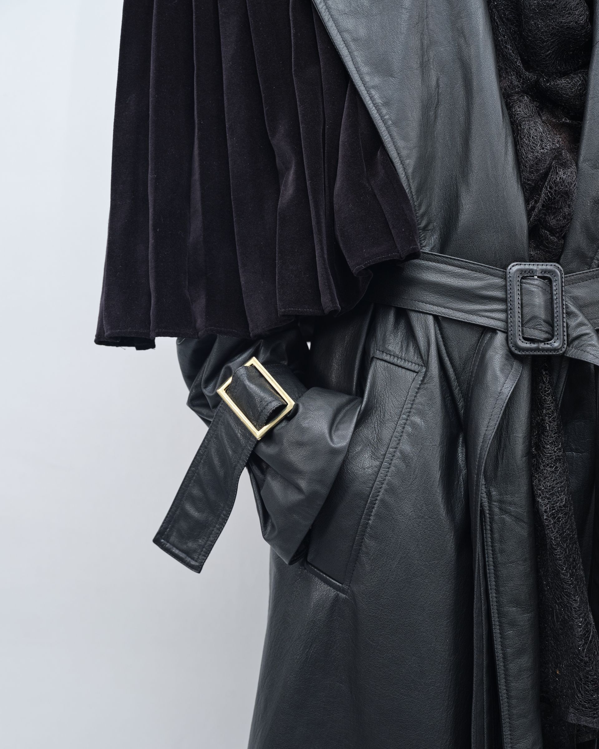 A close up of a black leather coat with a gold buckle