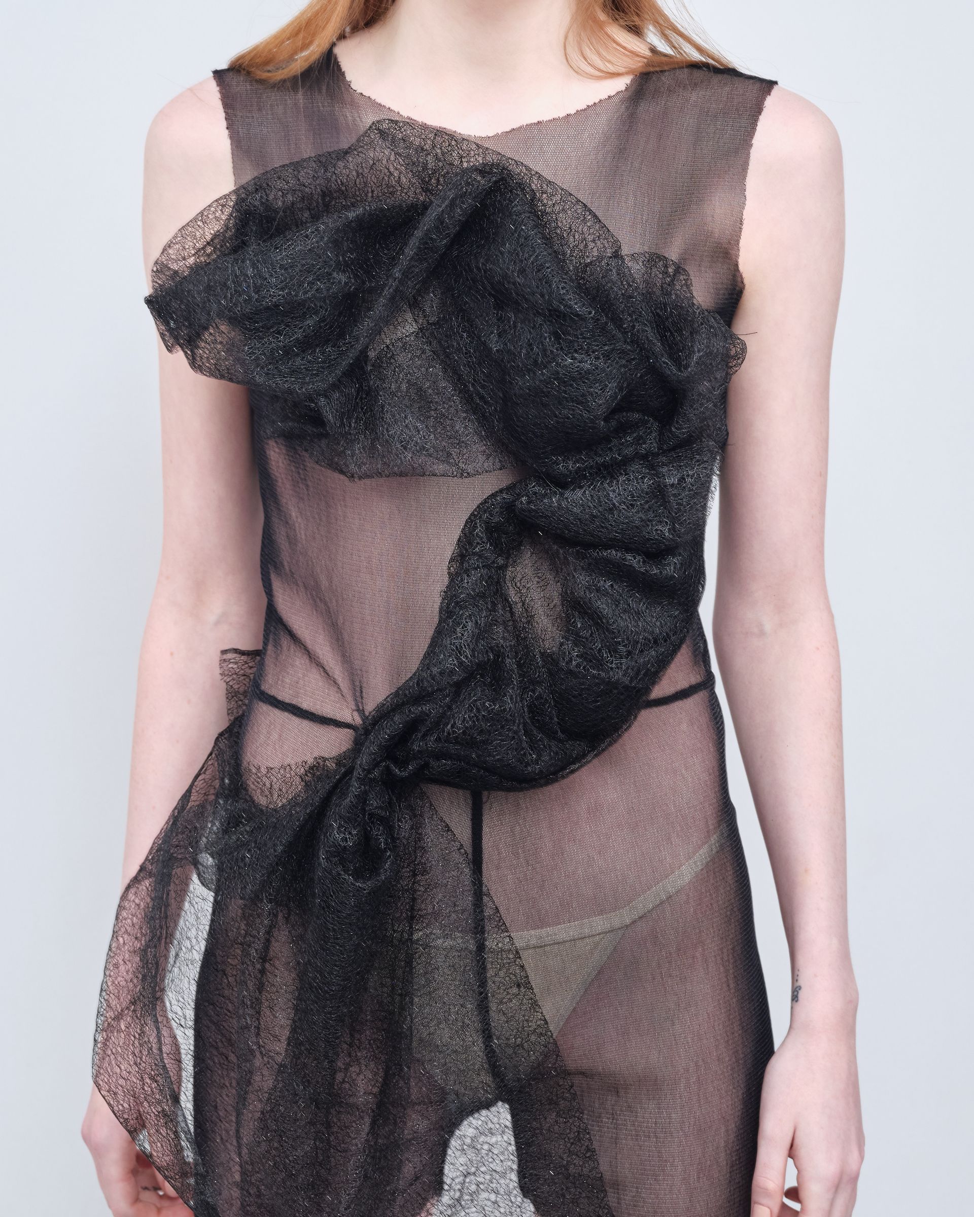 A woman is wearing a black dress with a bow on the front