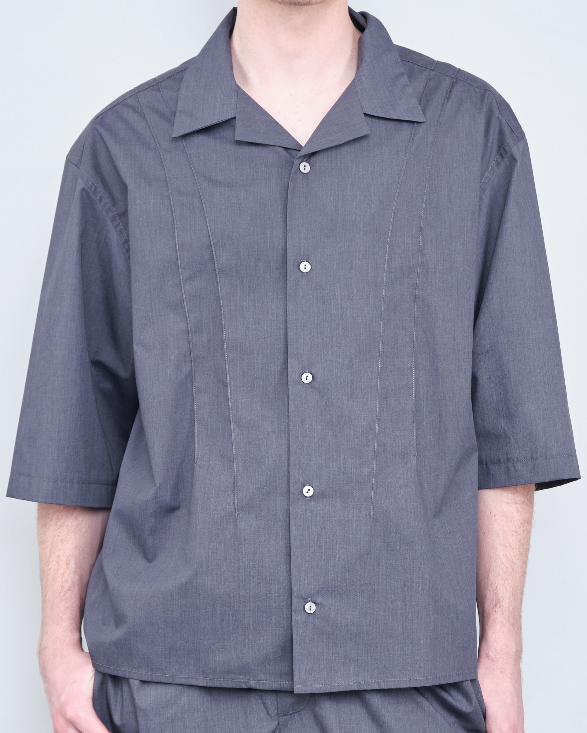 A man is wearing a grey shirt and grey shorts