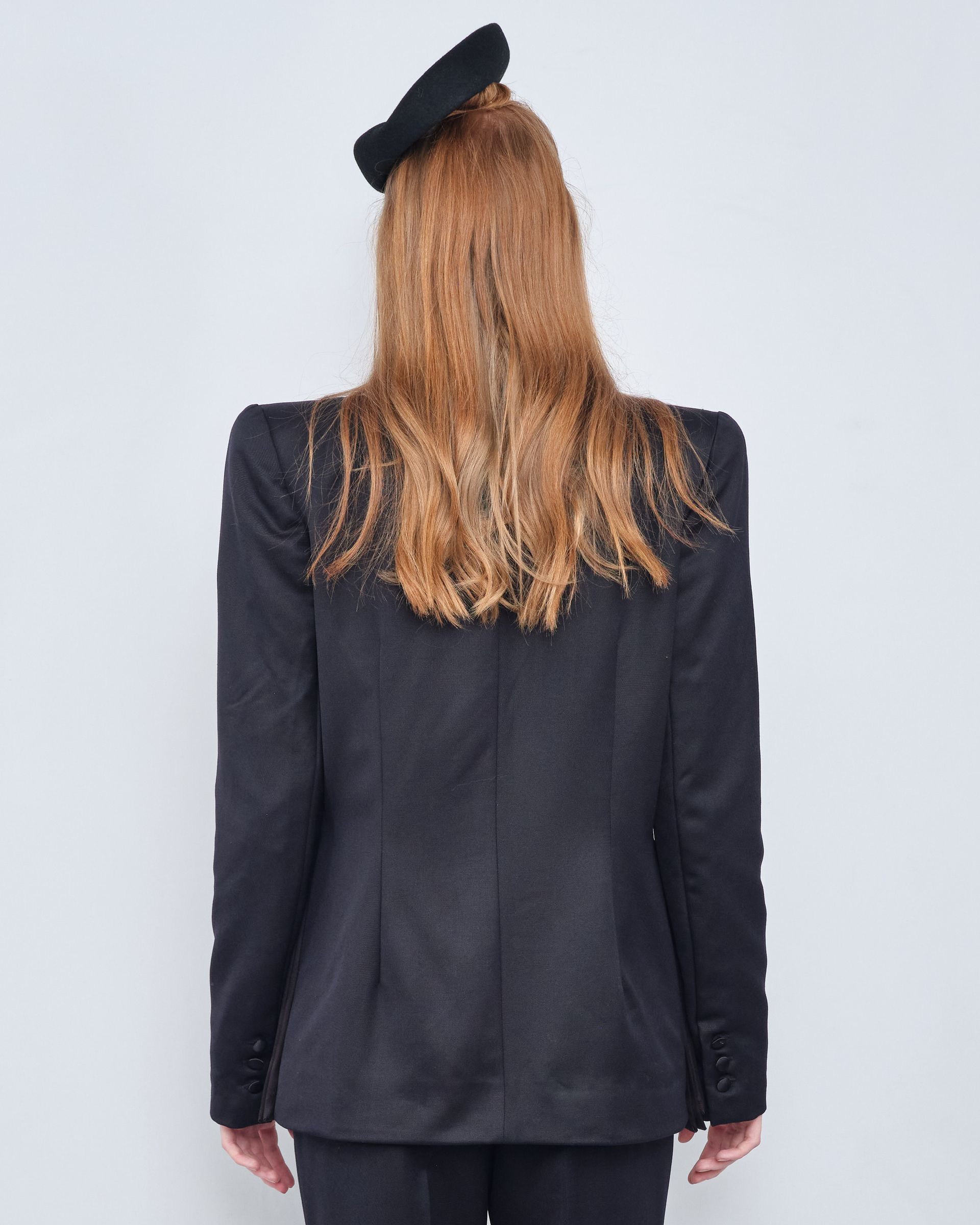 The back of a woman wearing a black jacket and beret