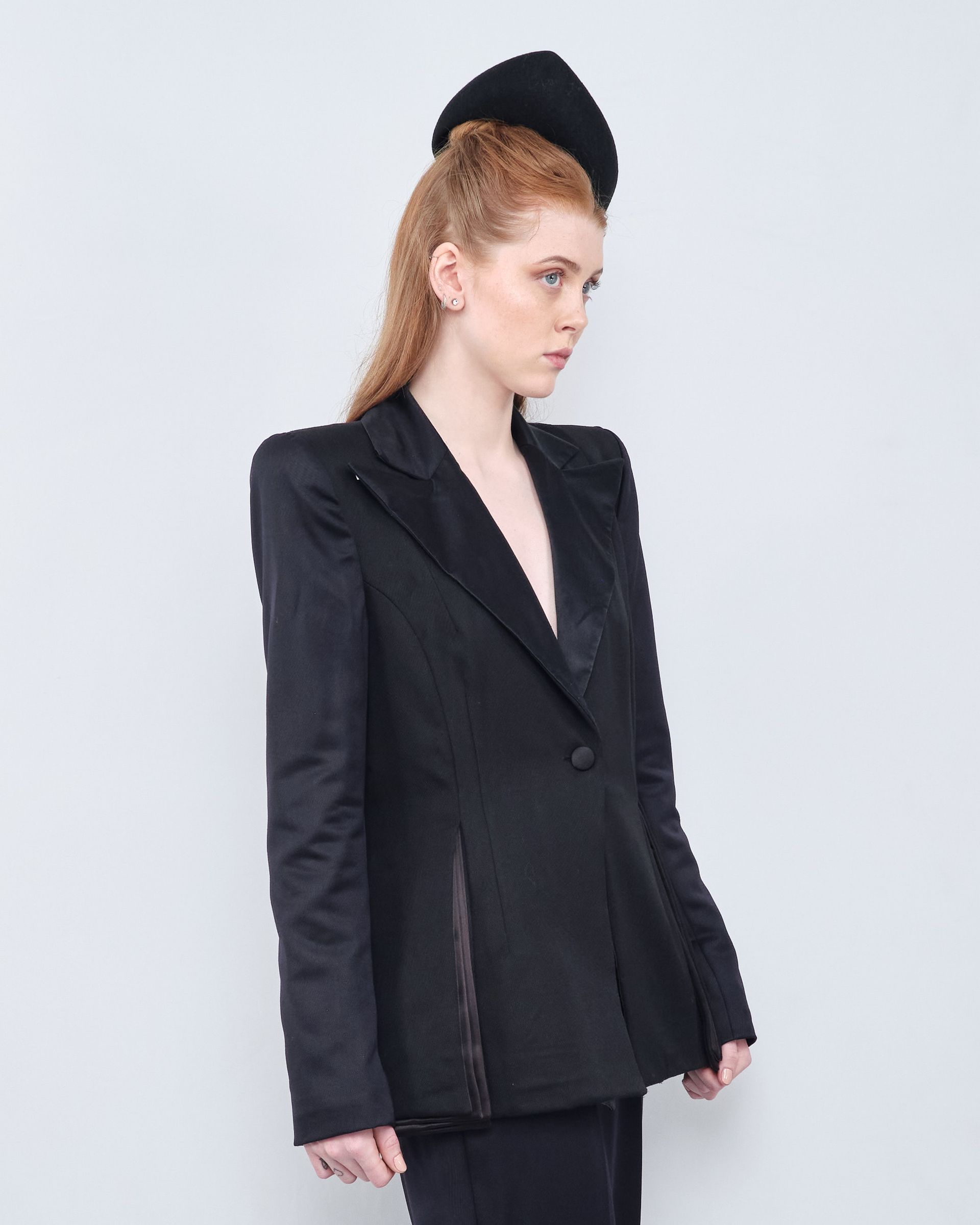 A woman is wearing a black tuxedo jacket and a black dress.