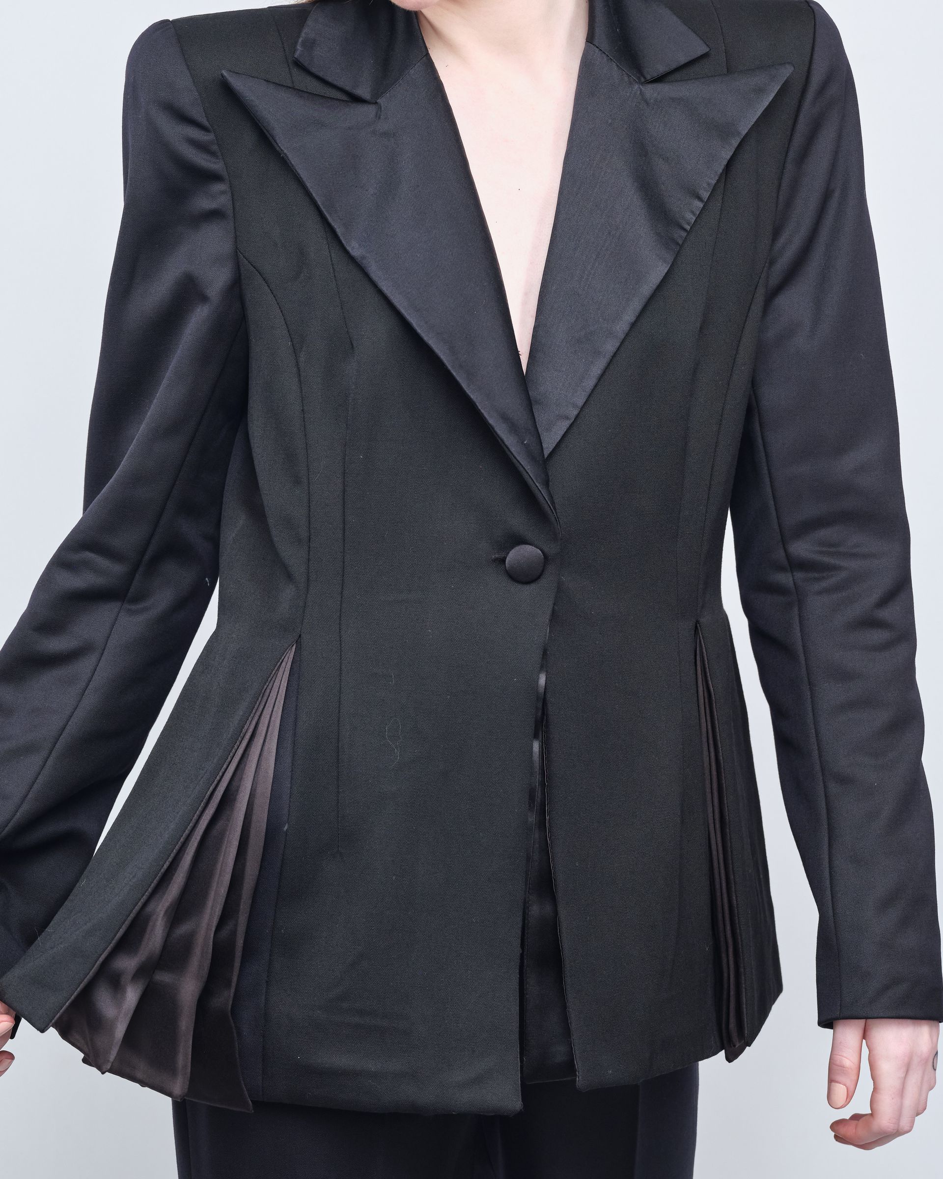 A woman is wearing a black jacket with a pleated back