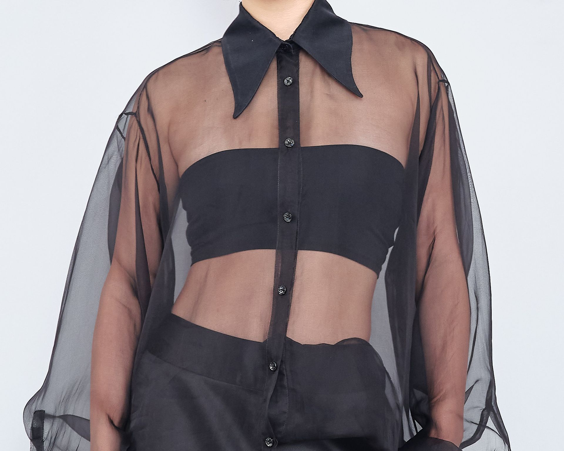 A woman is wearing a black shirt with sheer sleeves