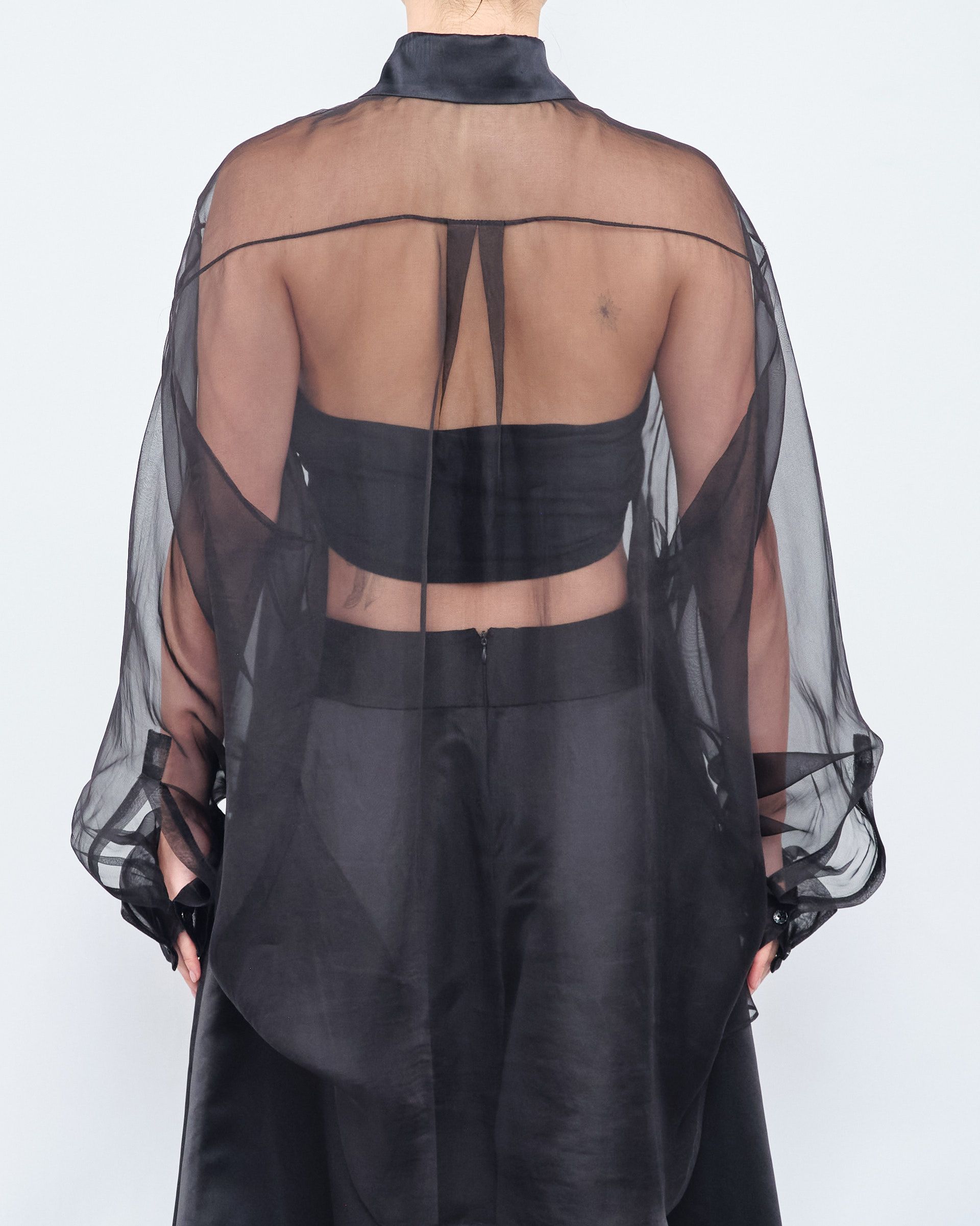 The back of a woman wearing a black sheer top