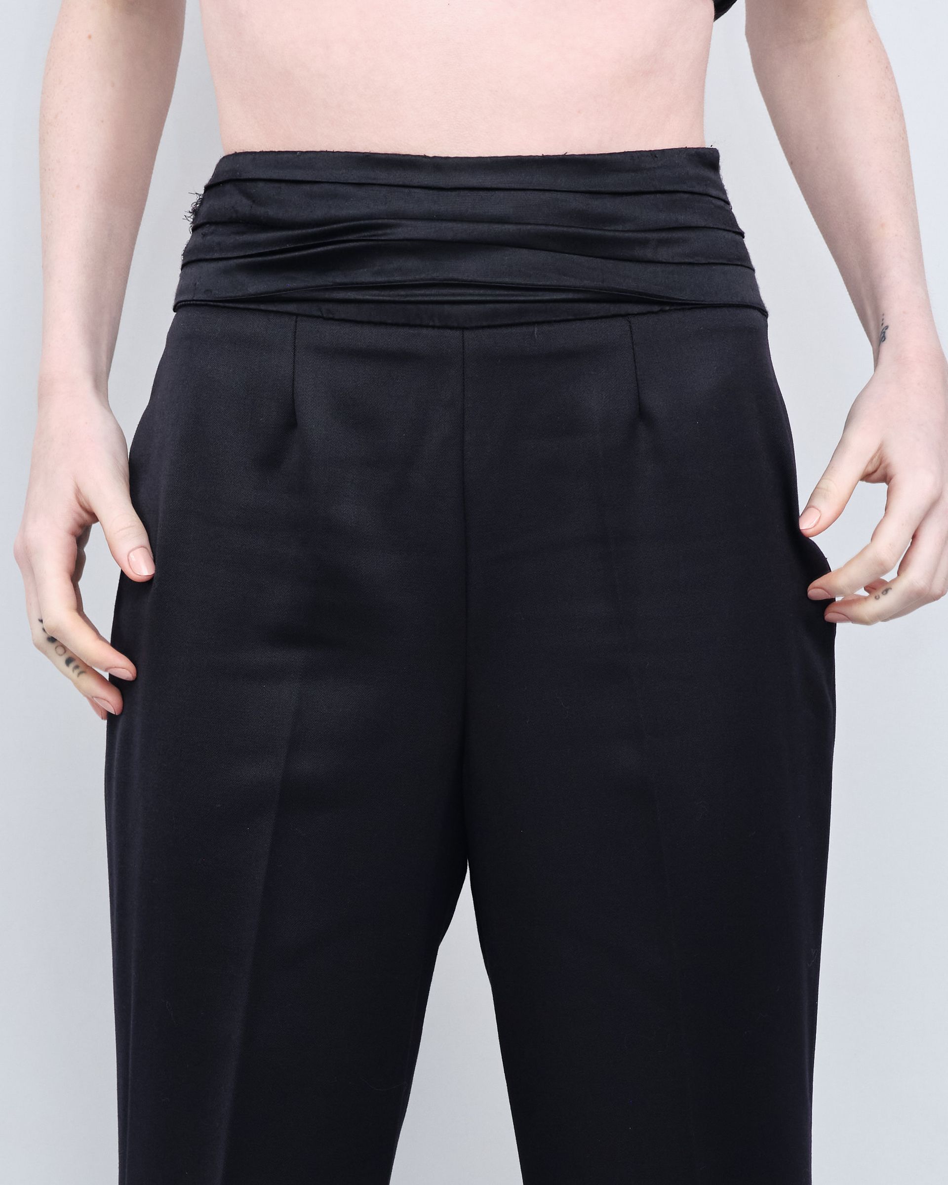 A woman with a tattoo on her hand is wearing black pants