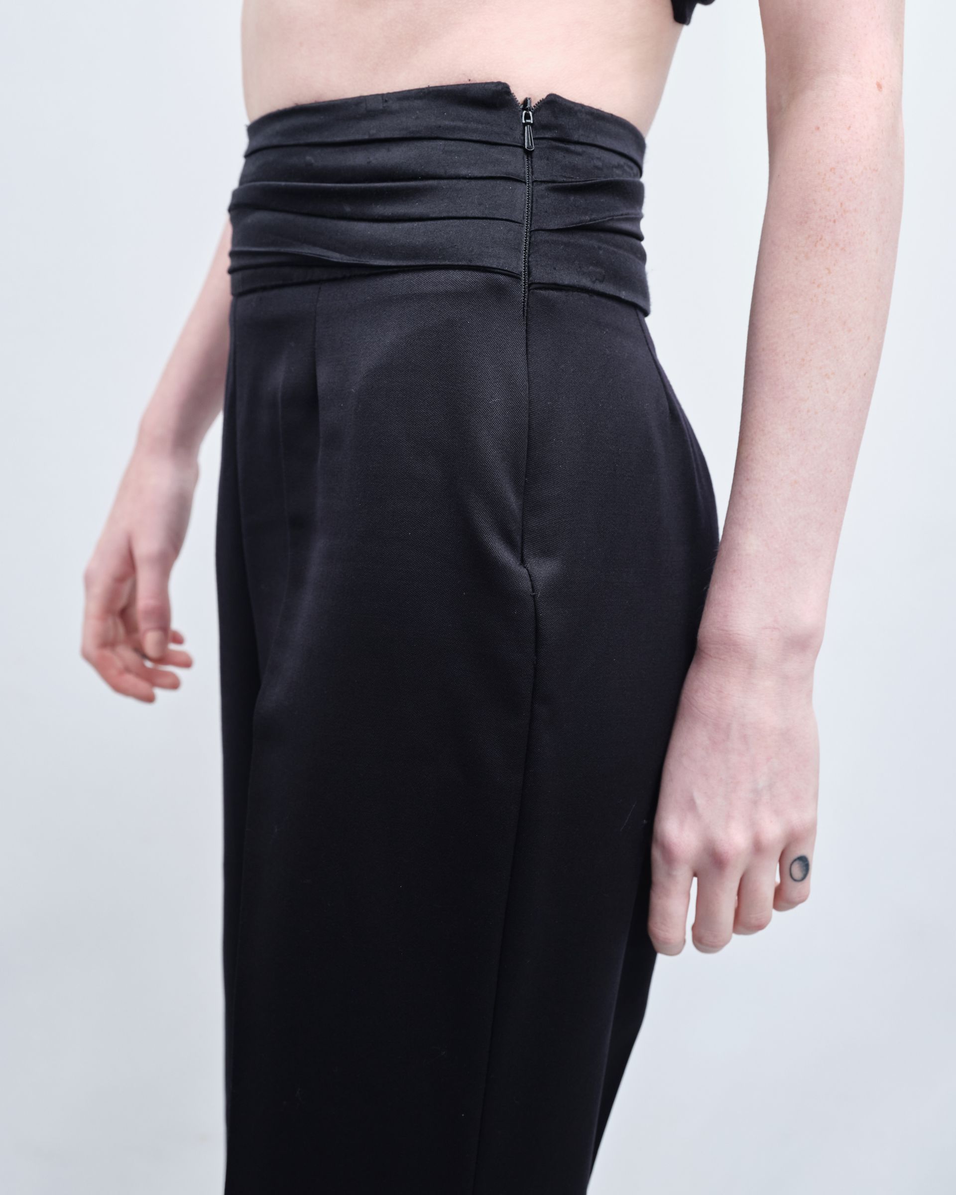 A woman wearing black pants has a ring on her finger