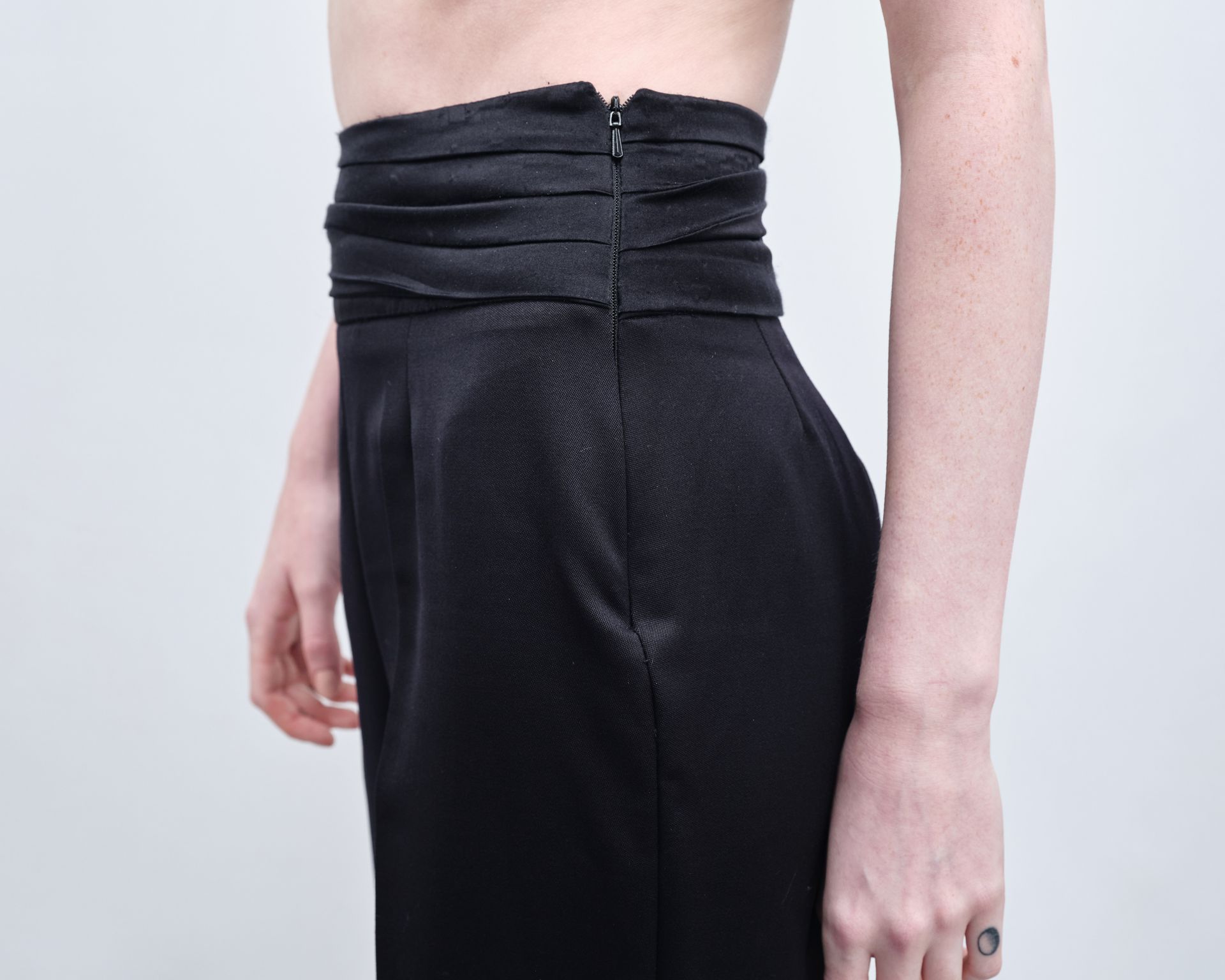 A woman with a tattoo on her hand is wearing black pants