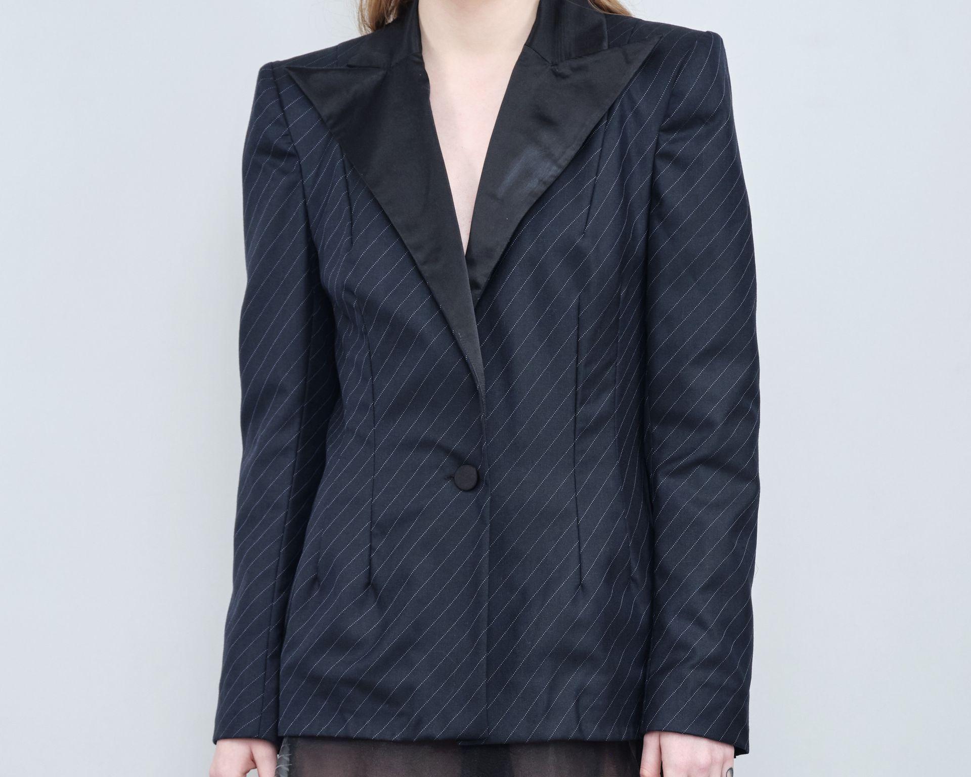 A woman is wearing a black tuxedo jacket